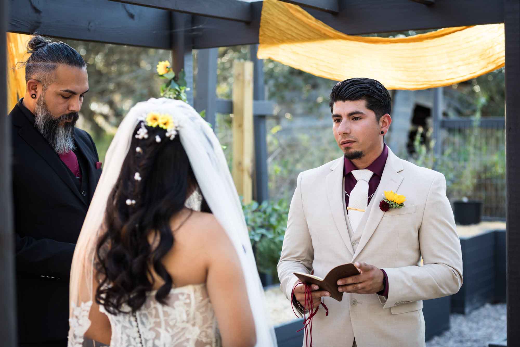 Groom holding vow book and saying vows to bride during ceremony in front of officiant at a San Antonio DIY wedding