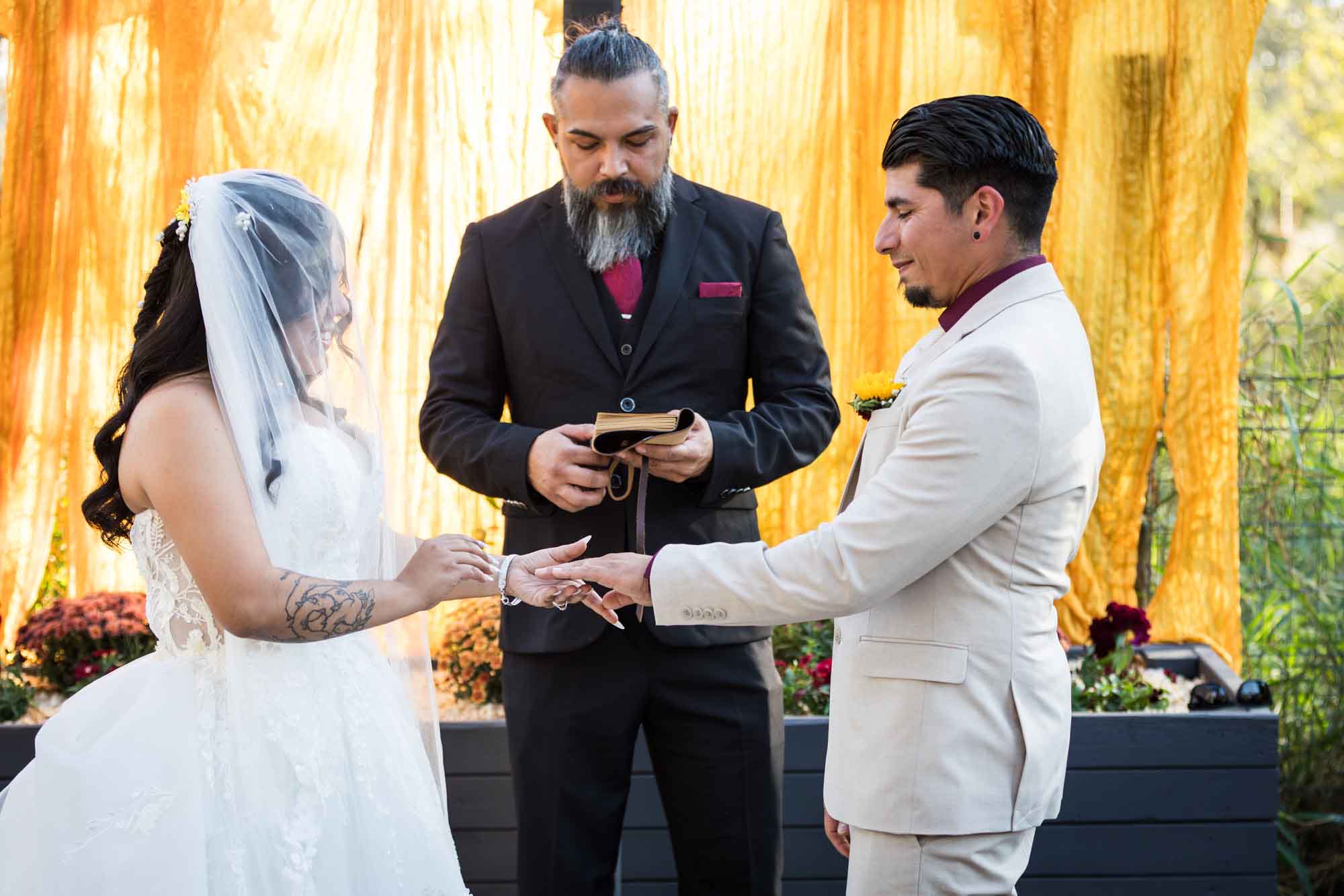 Bride about to put ring on groom's finger during ceremony in front of officiant at a San Antonio DIY wedding