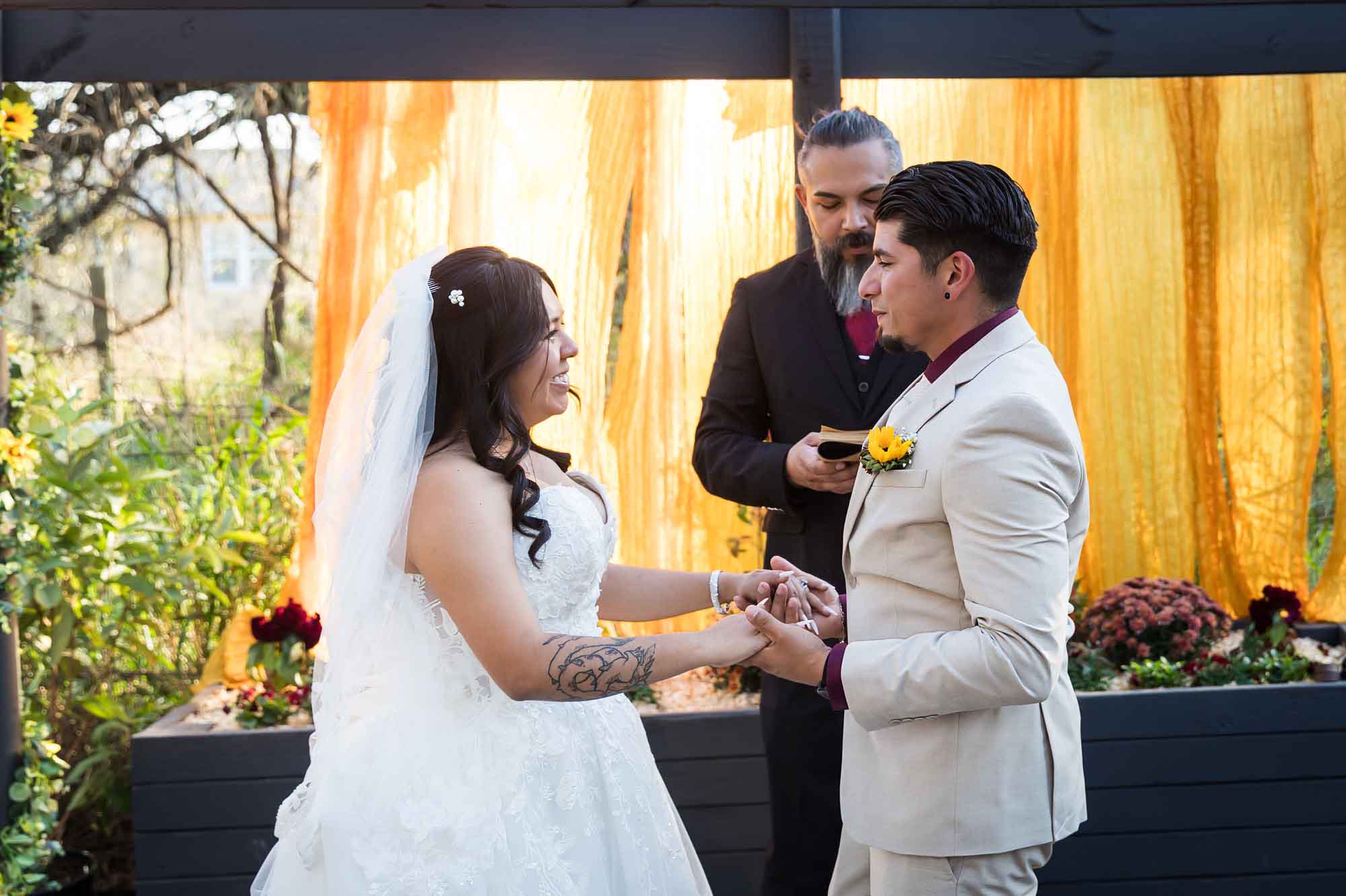 Bride and groom holding hands and looking at each other during ceremony in front of officiant at a San Antonio DIY wedding