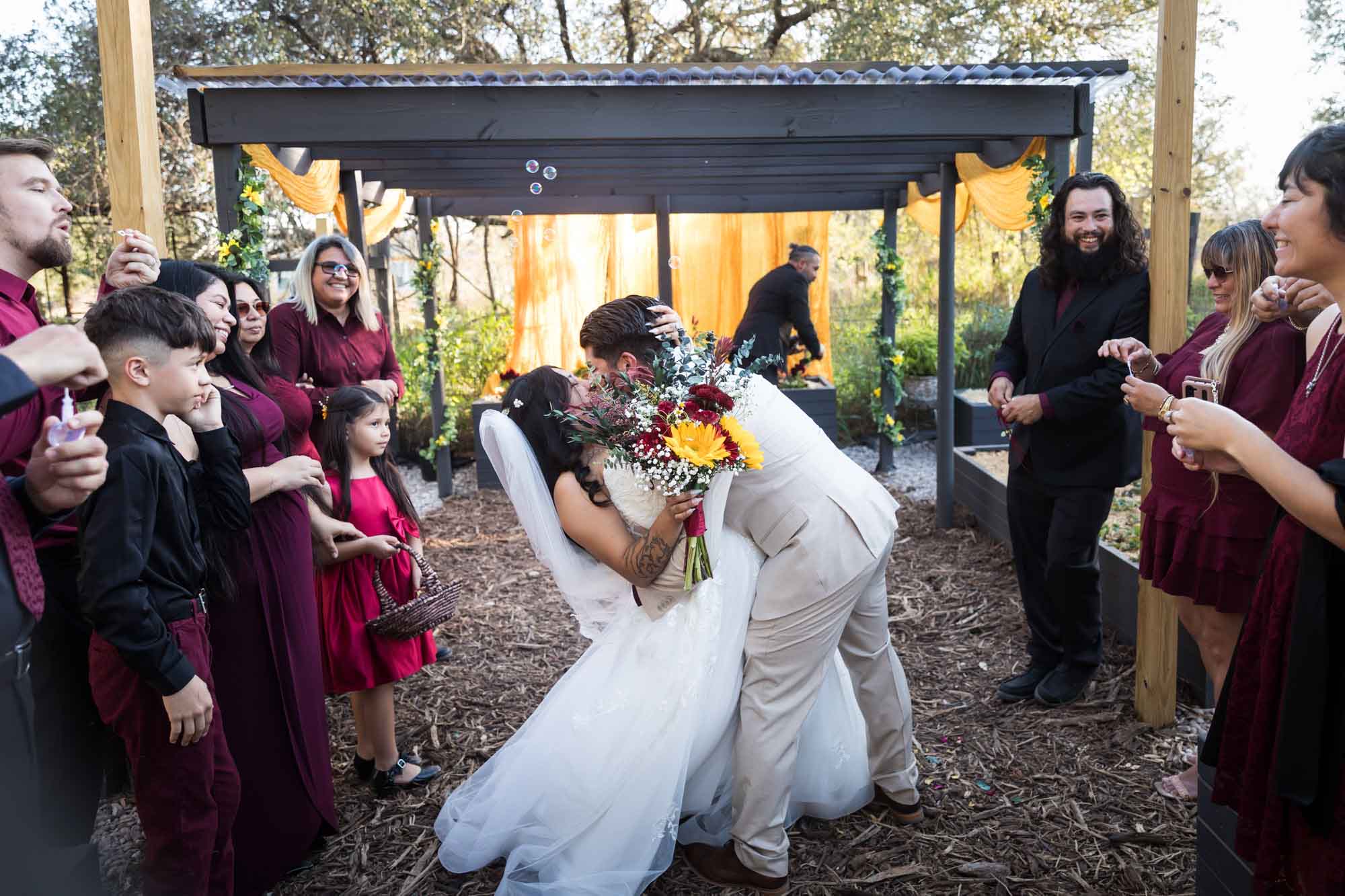 Bride and groom kissing in front of guests in aisle after ceremony at a San Antonio DIY wedding