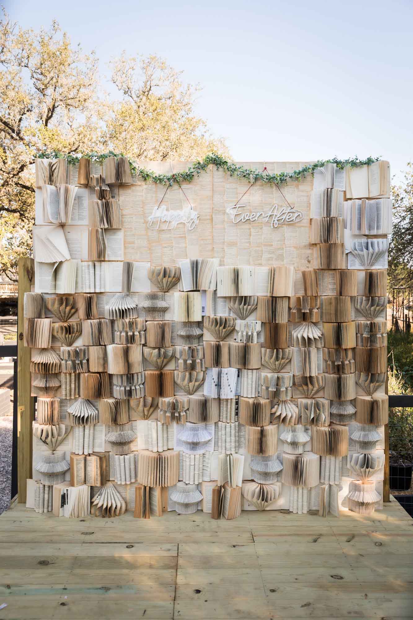 Book background with many open books and a neon sign that says 'Happily Ever After' at a San Antonio DIY wedding