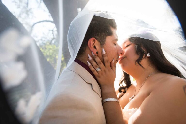 Bride and groom kissing under bride's veil at a San Antonio DIY wedding