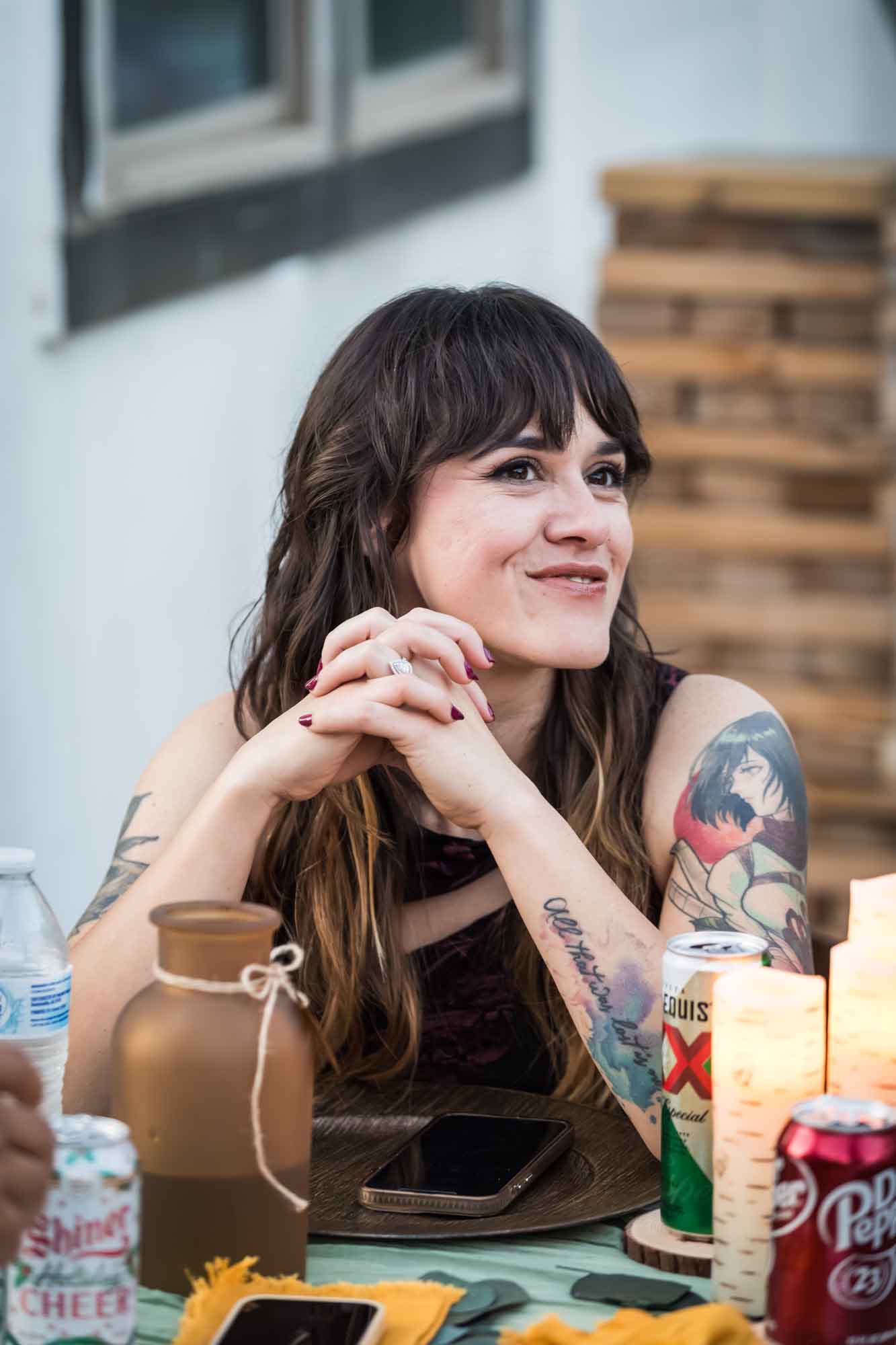 Female guest with long brown hair and tattoos seated at table at a San Antonio DIY wedding