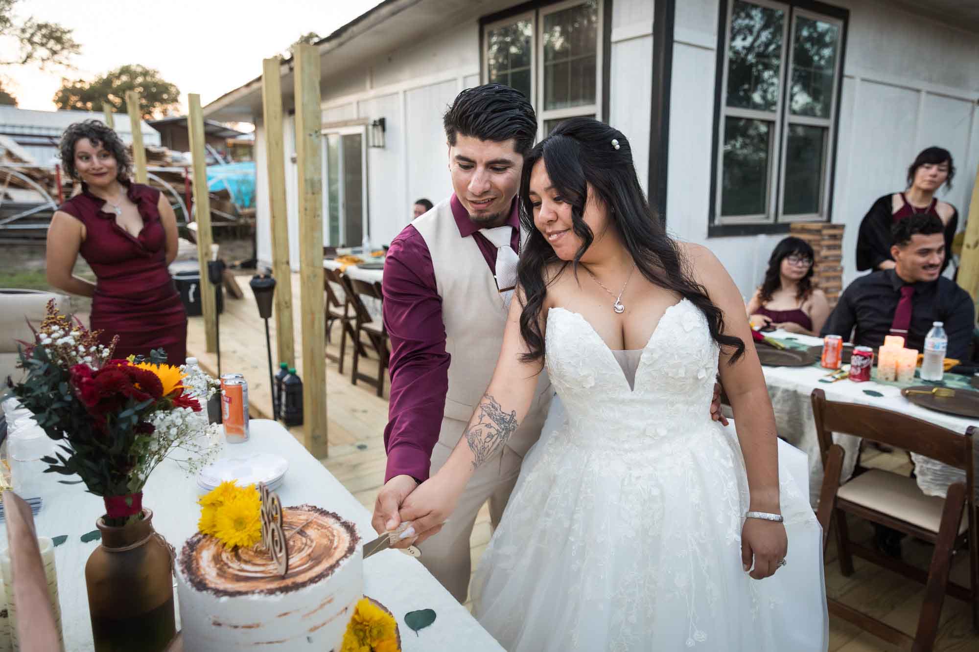 Bride and groom cutting wedding cake in front of guests at a San Antonio DIY wedding