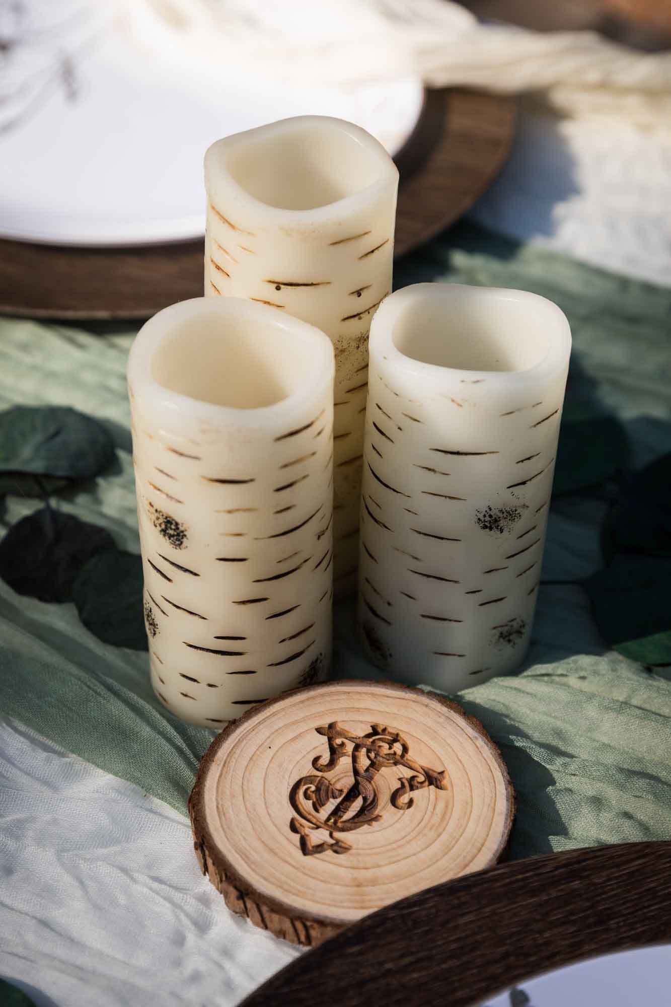 Wooden coaster with intricate monogram against faux wooden candles at a San Antonio DIY wedding