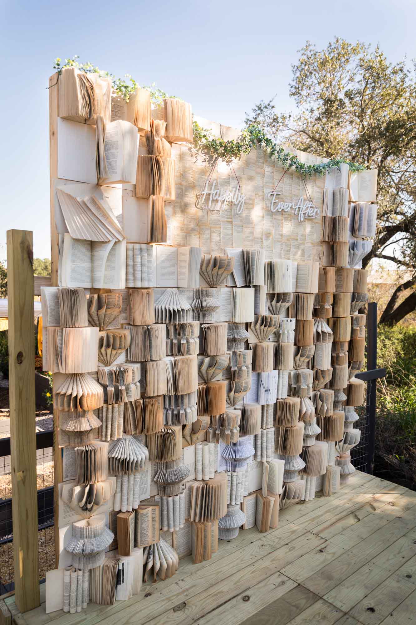Book background with many open books and a neon sign that says 'Happily Ever After' at a San Antonio DIY wedding