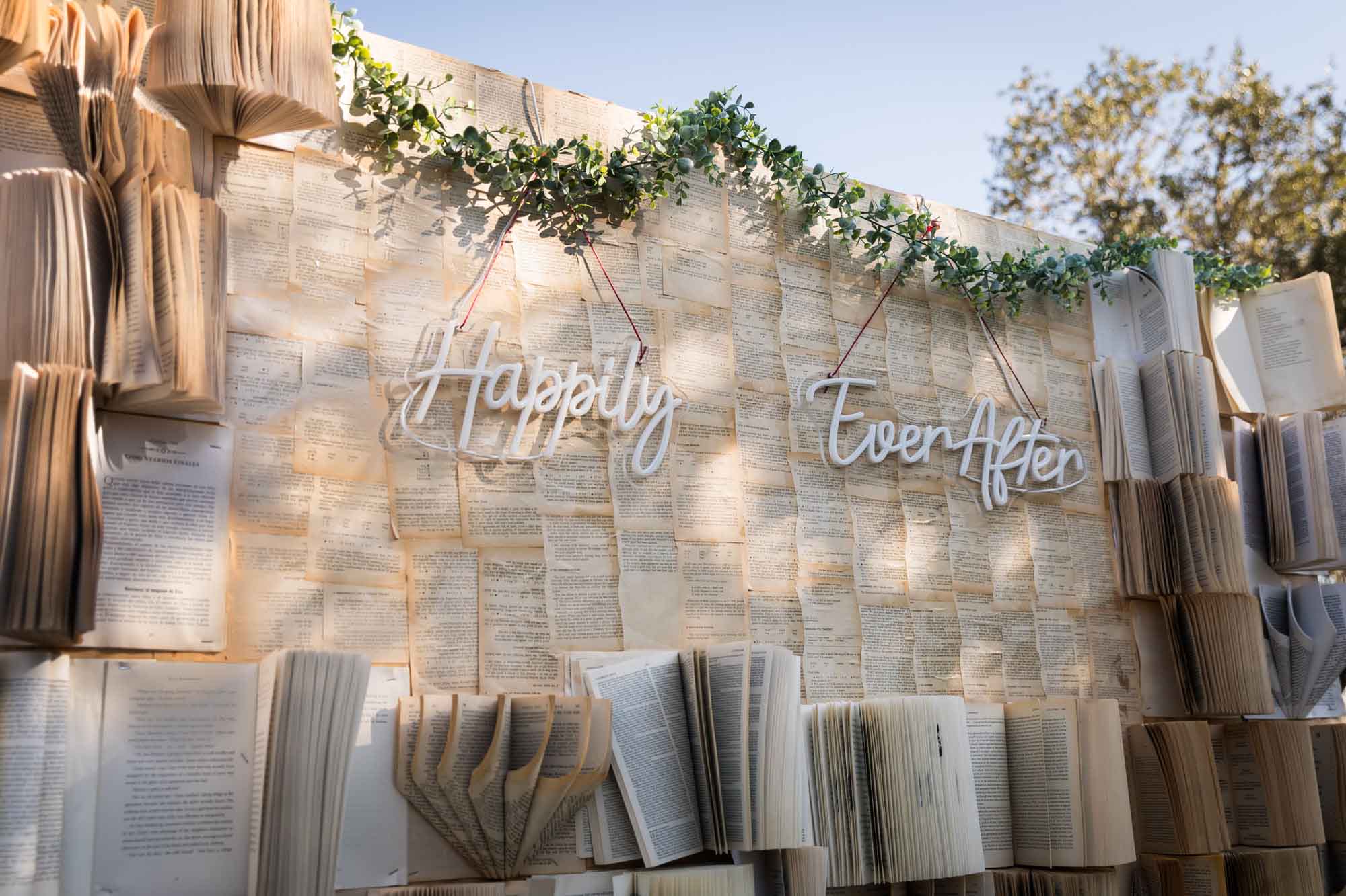Book background with many open books and a neon sign that says 'Happily Ever After' at a San Antonio DIY wedding
