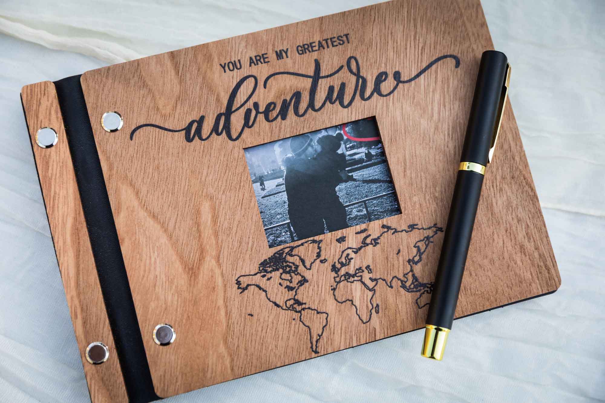 Guest book with wooden front and sign that says 'You are my greatest adventure' and black pen on front Table with wooden cutting board, card box, guest book, and guest book sign at a San Antonio DIY wedding