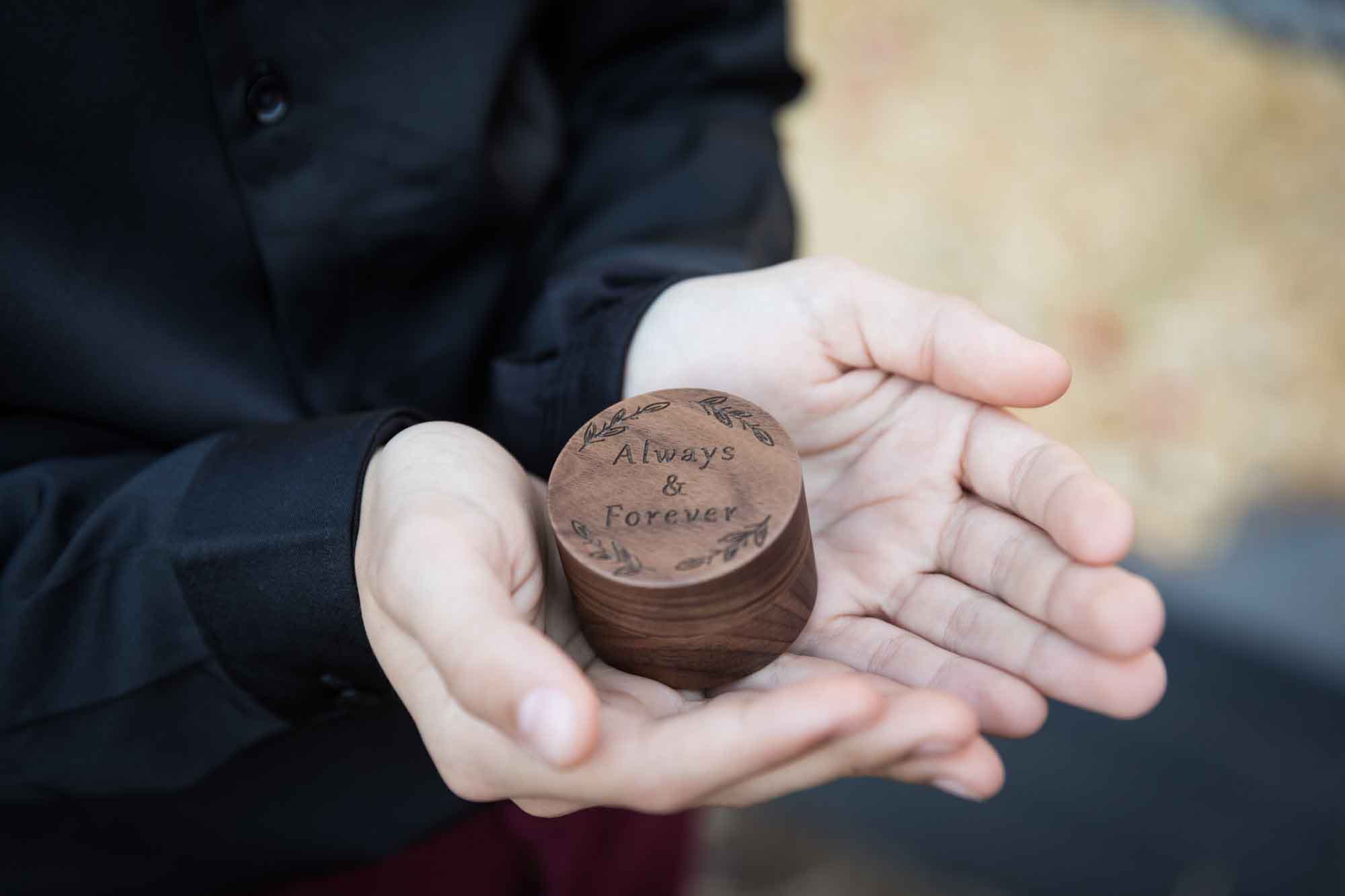 Close up of ring bearer holding round, wooden ring box at a San Antonio DIY wedding