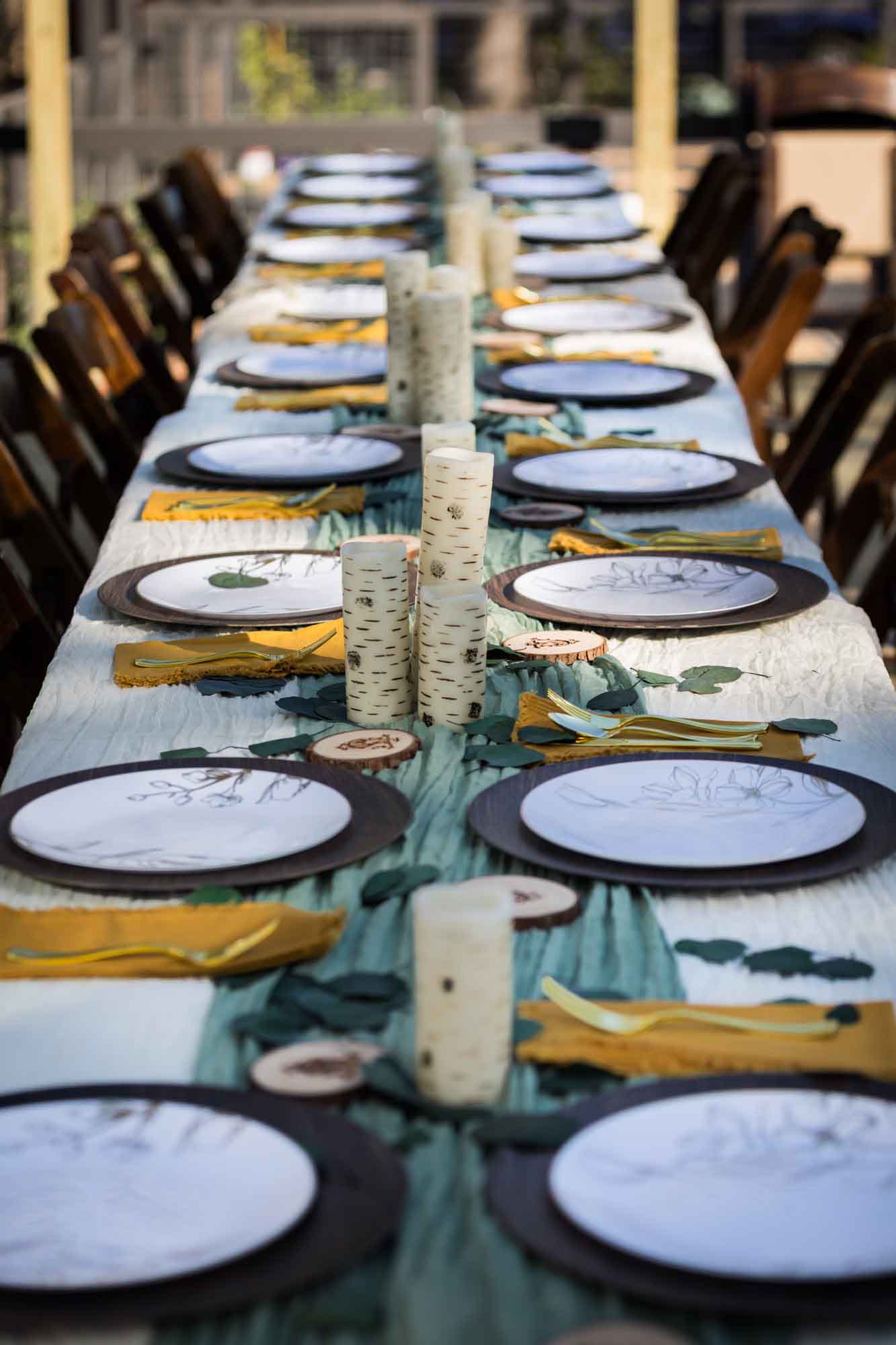 Table with green runner, plastic plates, candles, and wooden coasters at a San Antonio DIY wedding