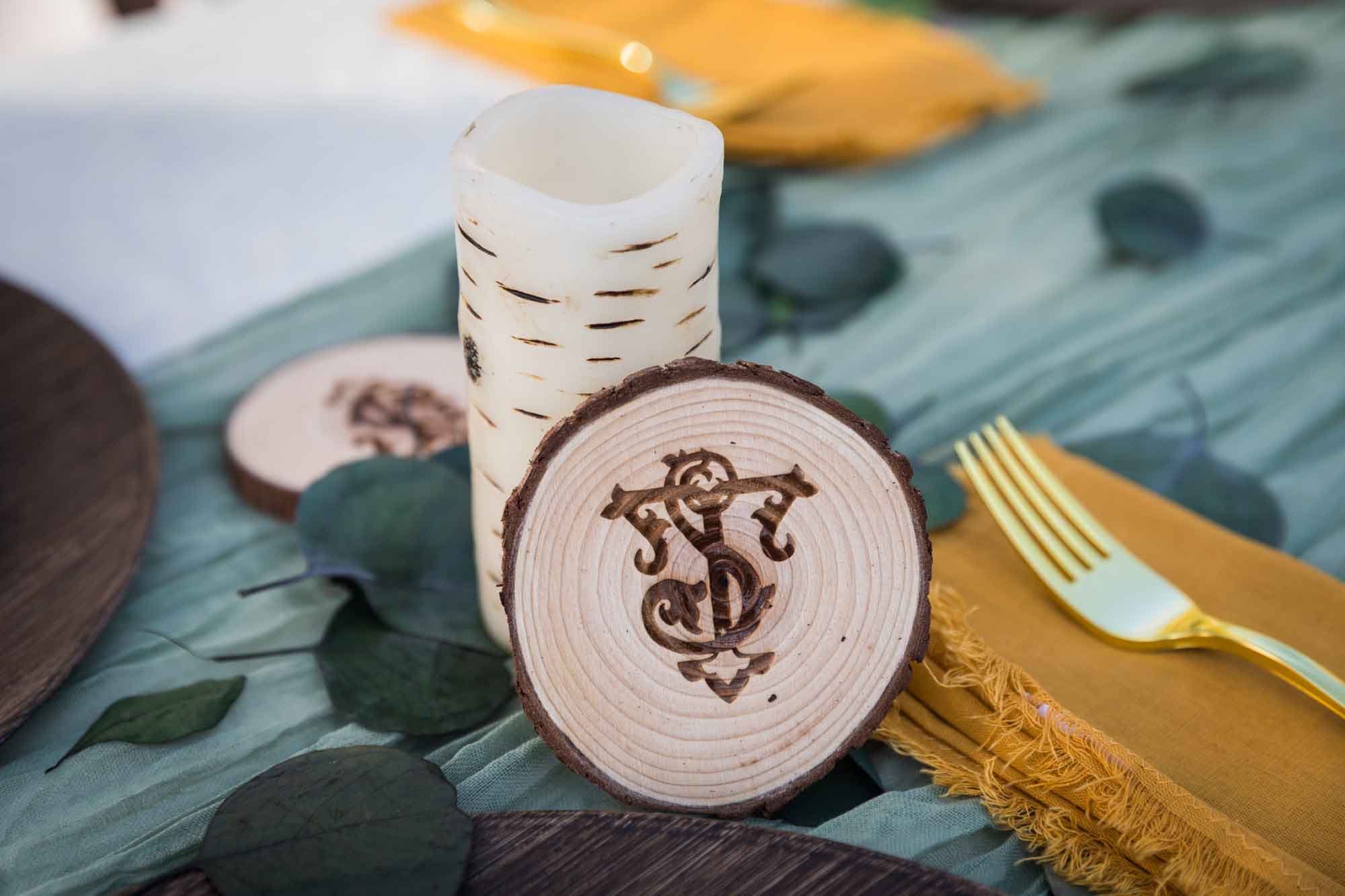 Wooden coaster with intricate monogram against candle at a San Antonio DIY wedding