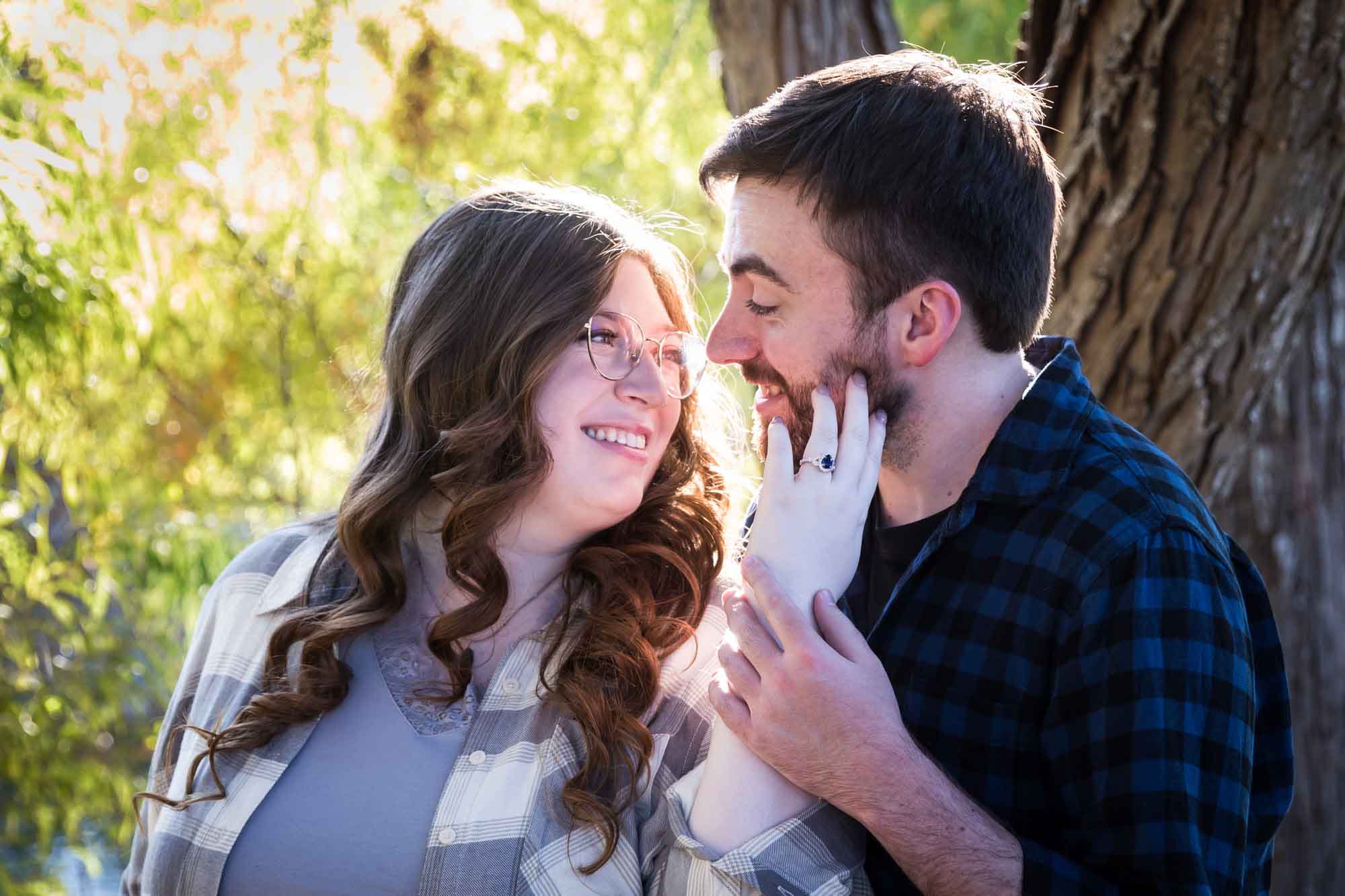 Boerne engagement photos of couple wearing plaid shirts hugging in front of trees in River Road Park