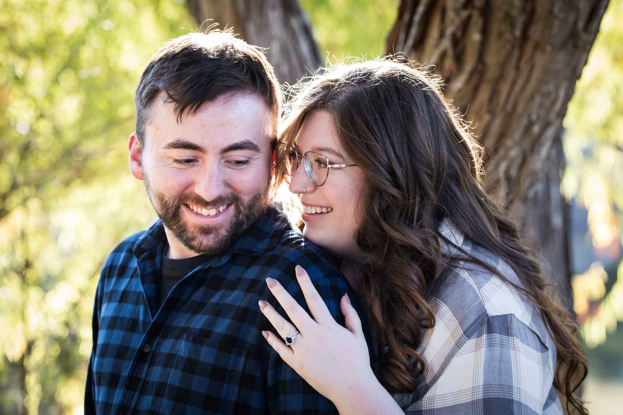 Boerne engagement photos of couple wearing plaid shirts hugging in front of trees in River Road Park