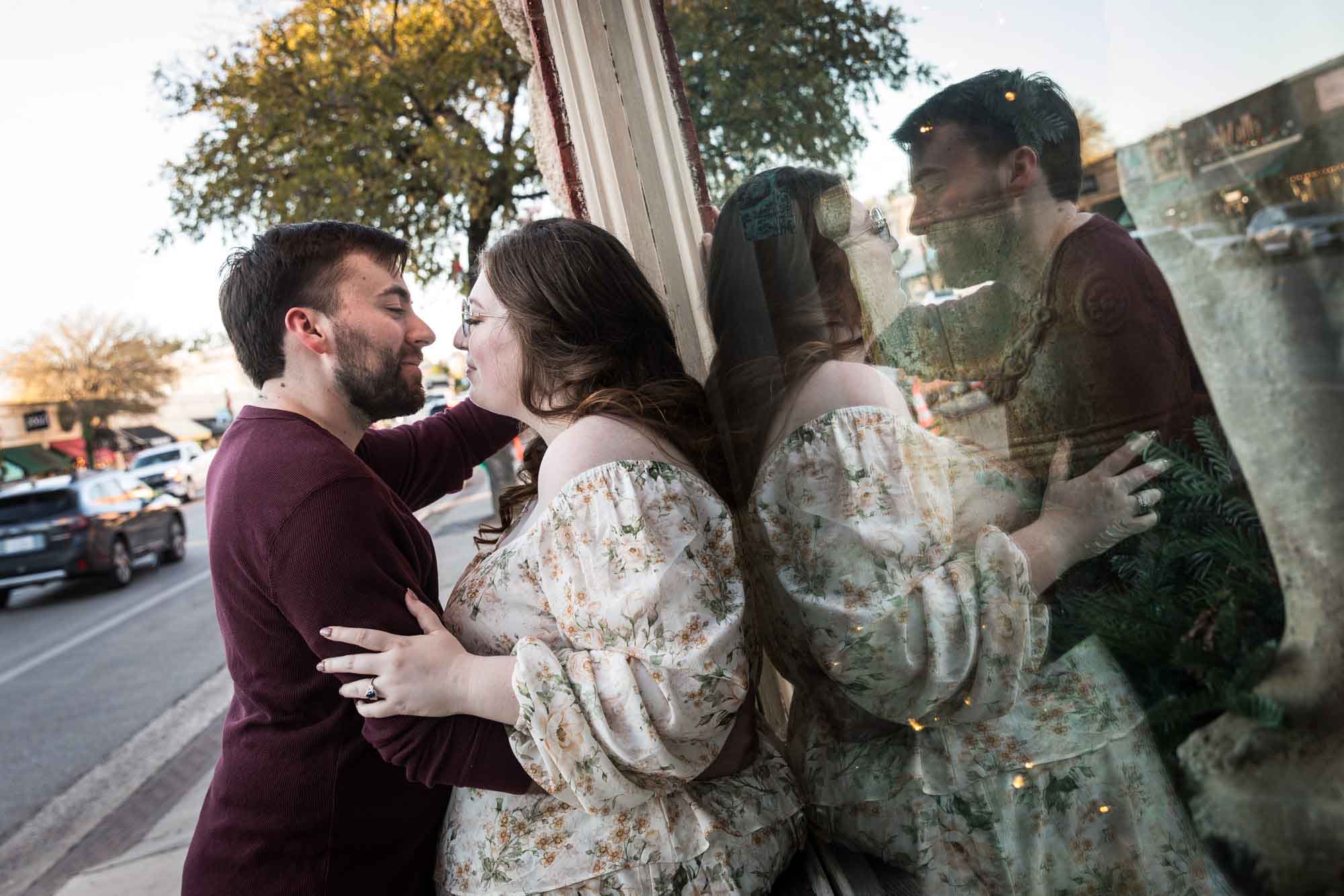 Boerne engagement photos of couple leaning up against reflective window on Main Street
