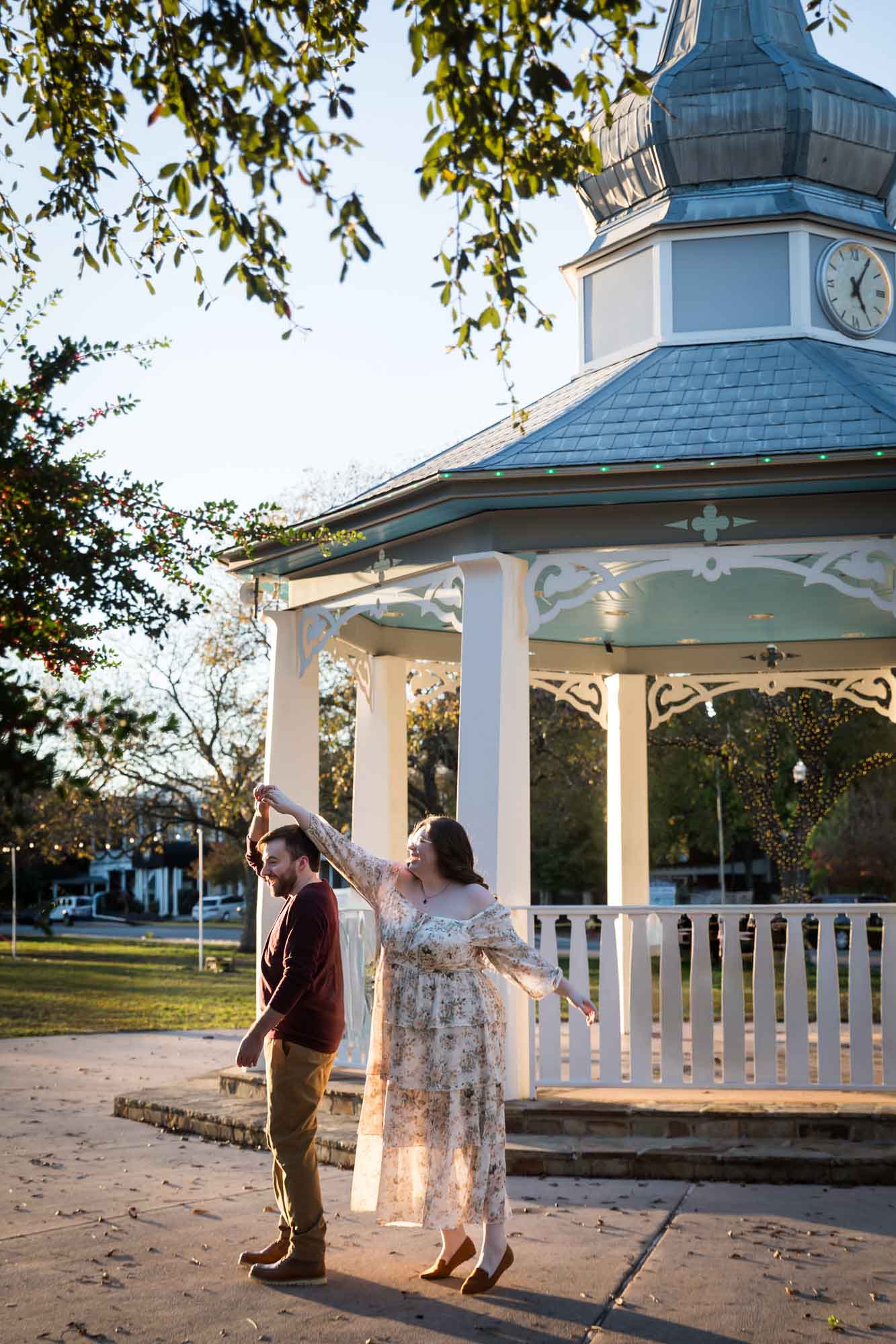 Boerne engagement photos of woman and man dancing at sunset in front of gazebo in Main Plaza