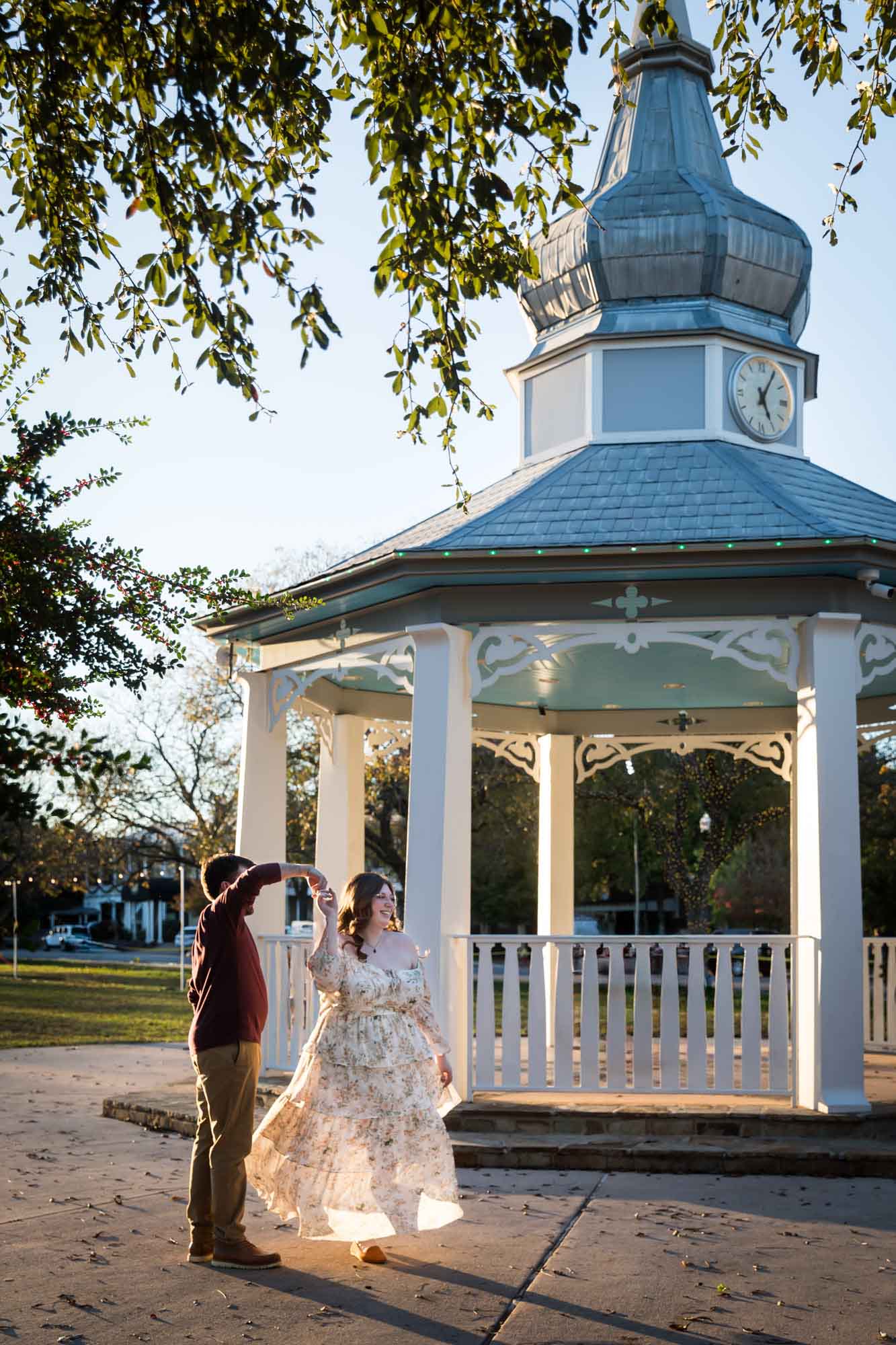 Boerne engagement photos of woman and man dancing at sunset in front of gazebo in Main Plaza
