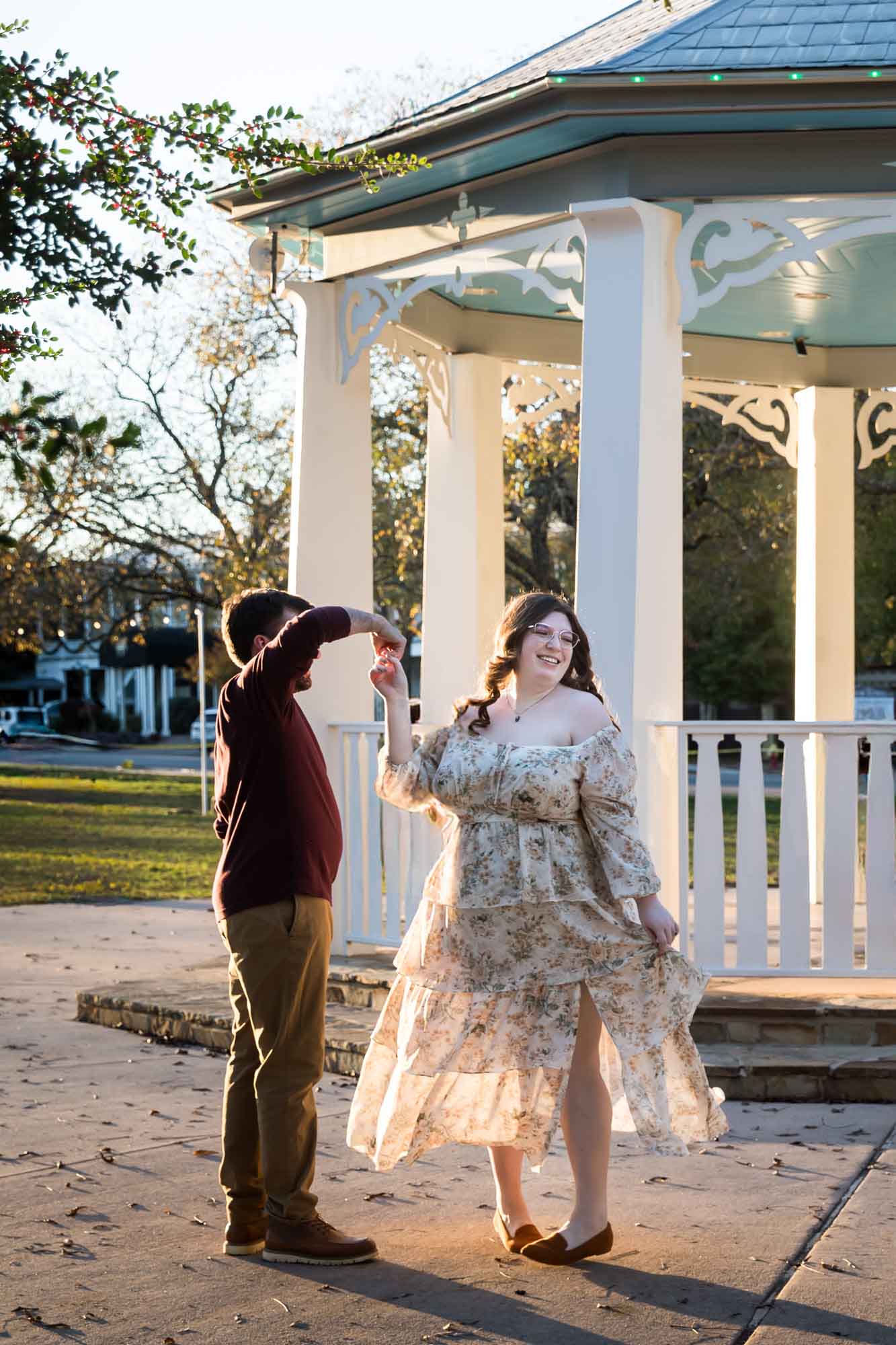 Boerne engagement photos of woman and man dancing at sunset in front of gazebo in Main Plaza