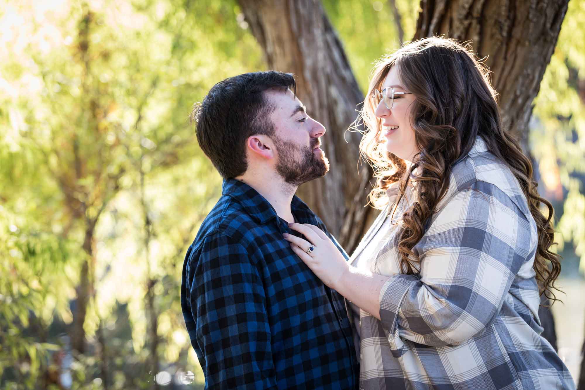 Boerne engagement photos of couple wearing plaid shirts hugging in front of trees in River Road Park