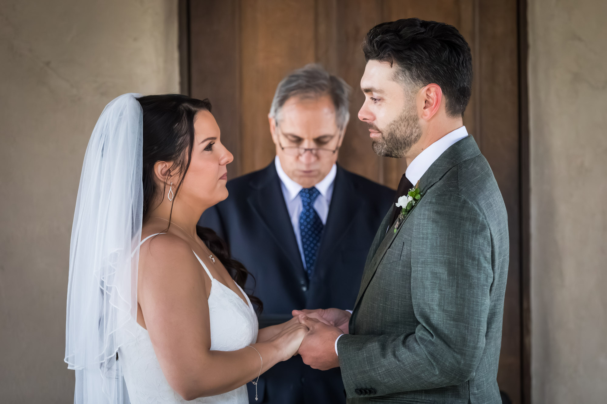 Bride and groom holding hands in front of officiant during ceremony at a Chapel Dulcinea wedding