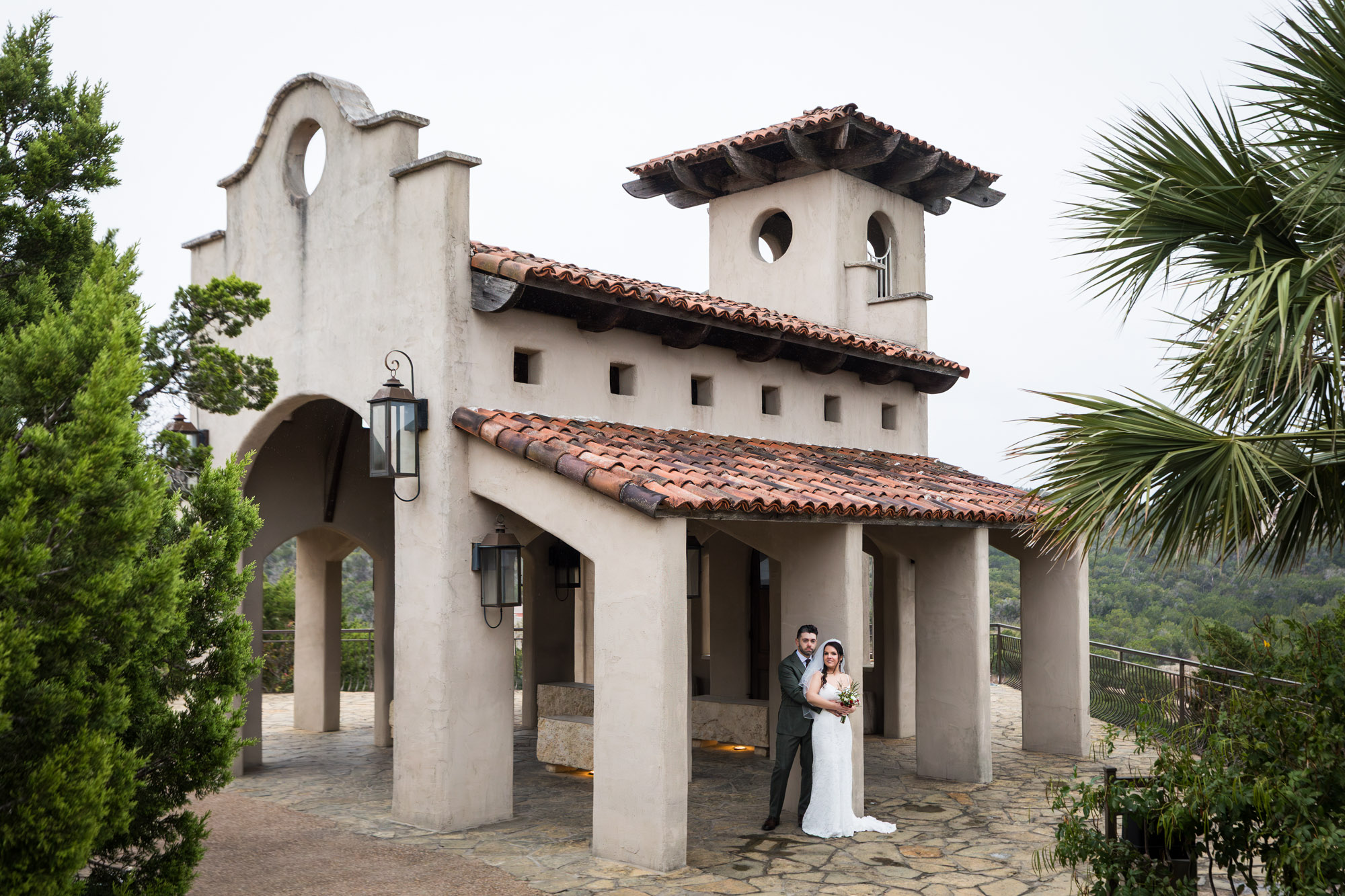 Bride wearing veil and groom standing by column beside chapel at a Chapel Dulcinea wedding