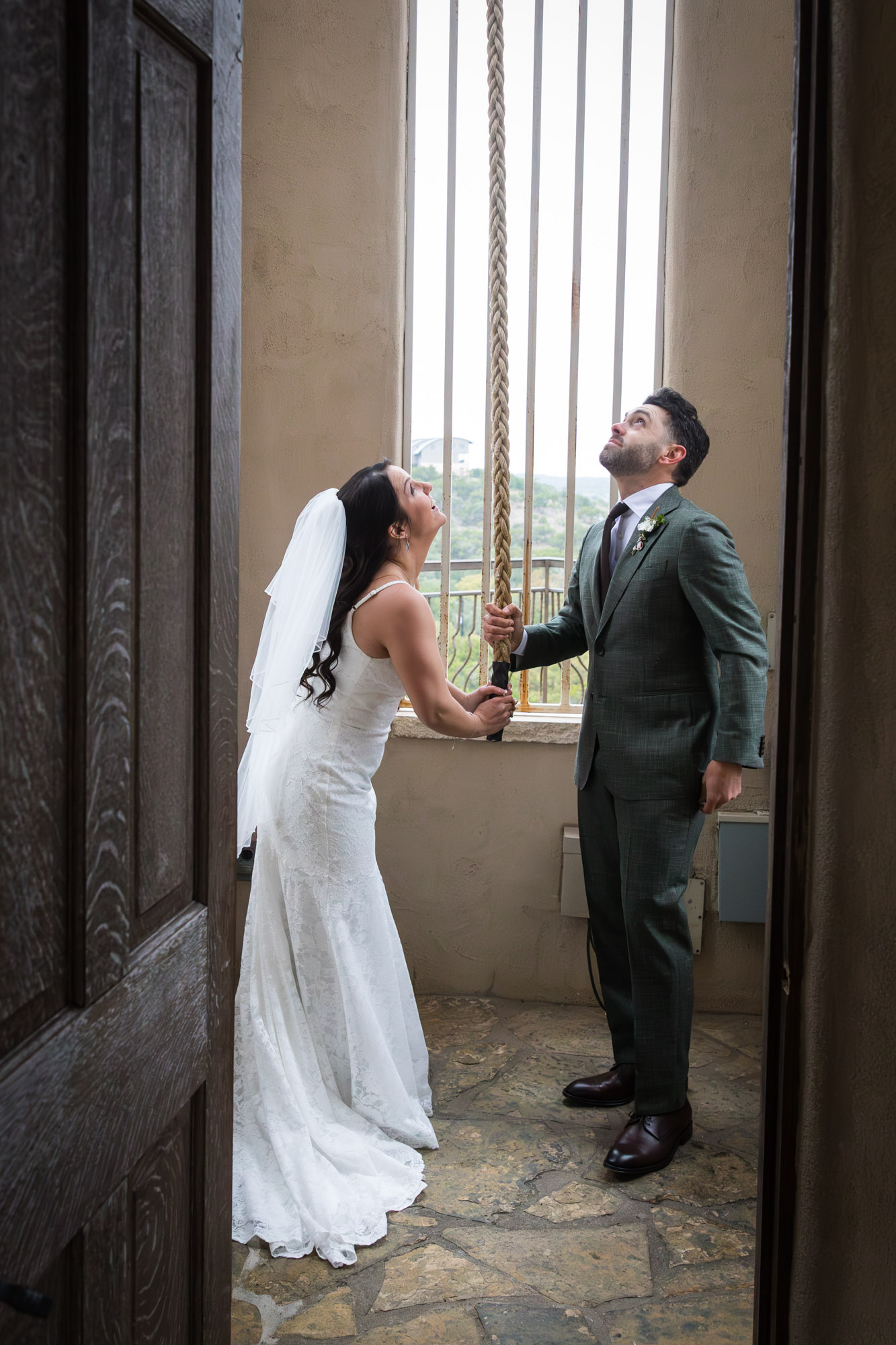 Bride wearing veil and groom ringing bell in room in front of window at a Chapel Dulcinea wedding