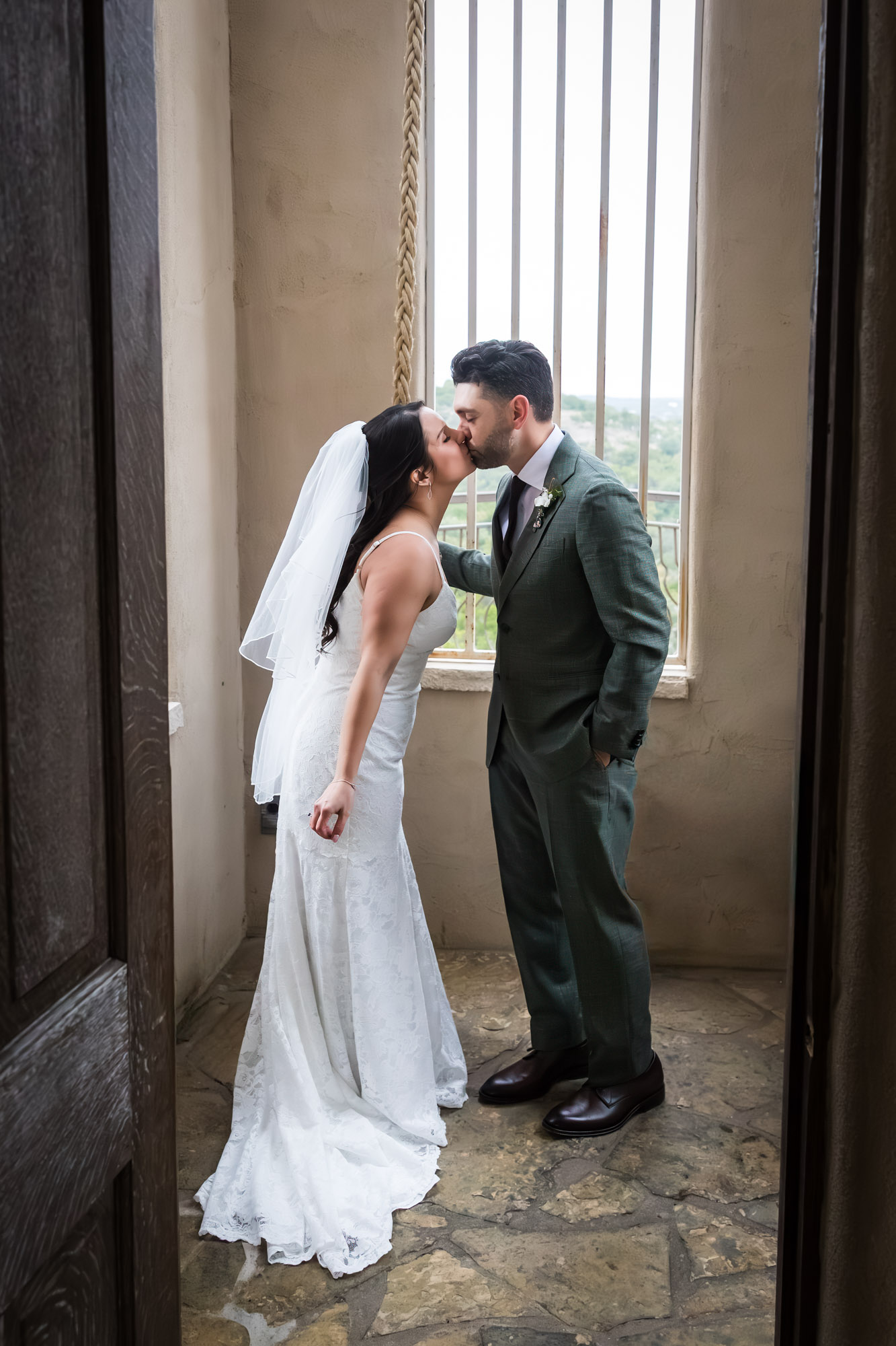 Bride wearing veil kissing groom while ringing bell at a Chapel Dulcinea wedding