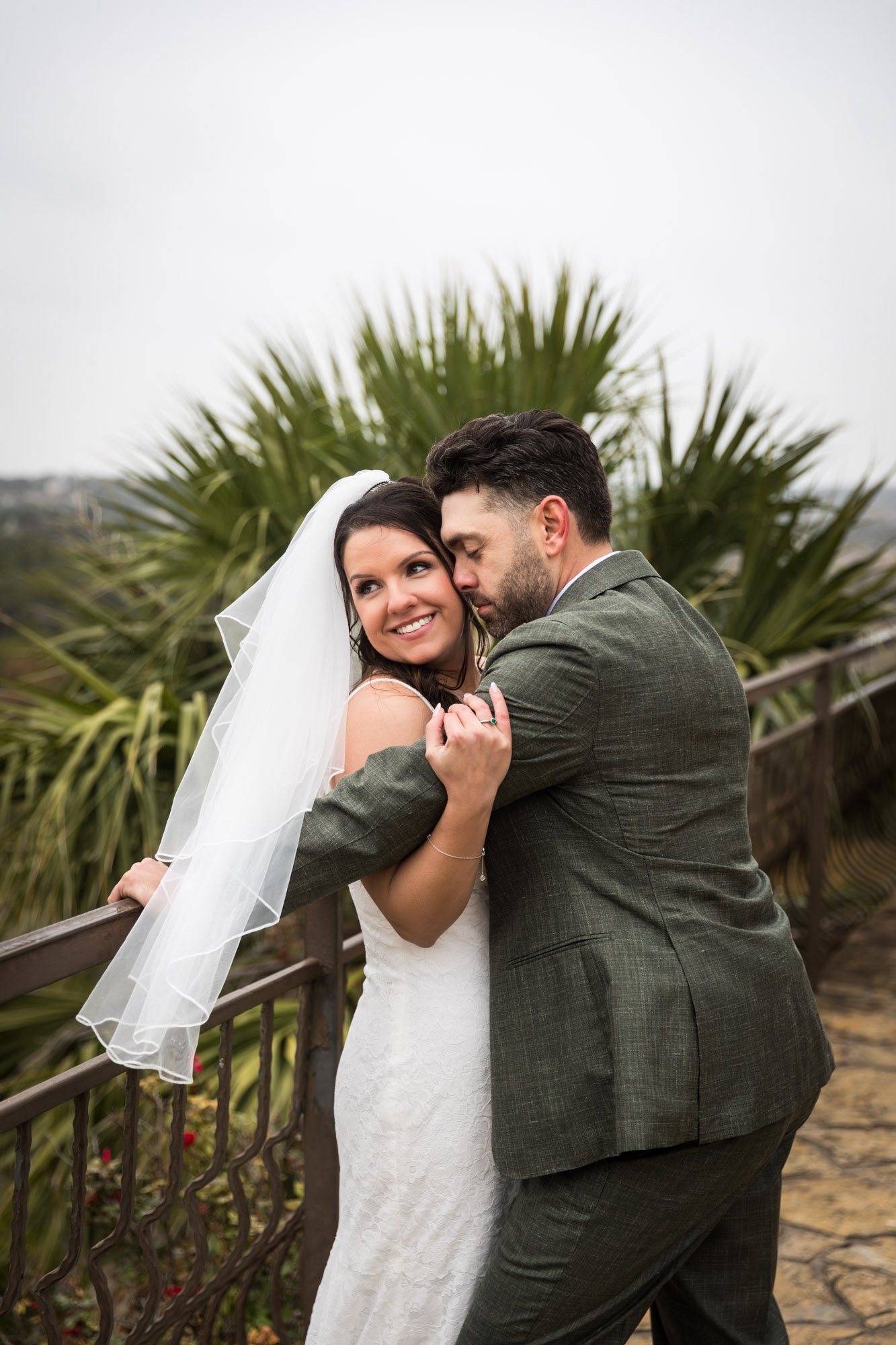 Bride wearing veil hugging groom against railing at a Chapel Dulcinea wedding