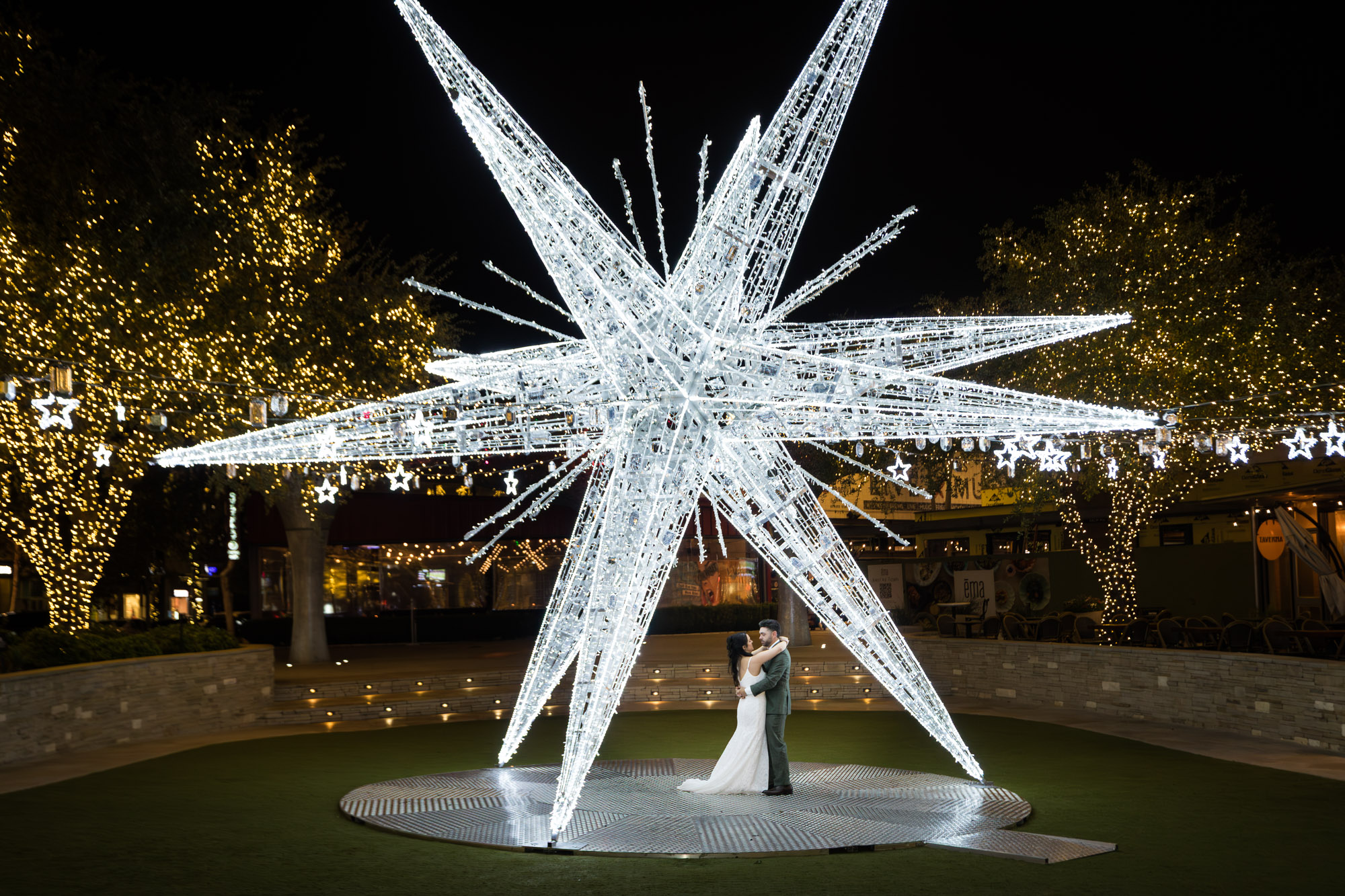 Bride and groom dancing under large white star lit up outside in patio of the Domain in Austin