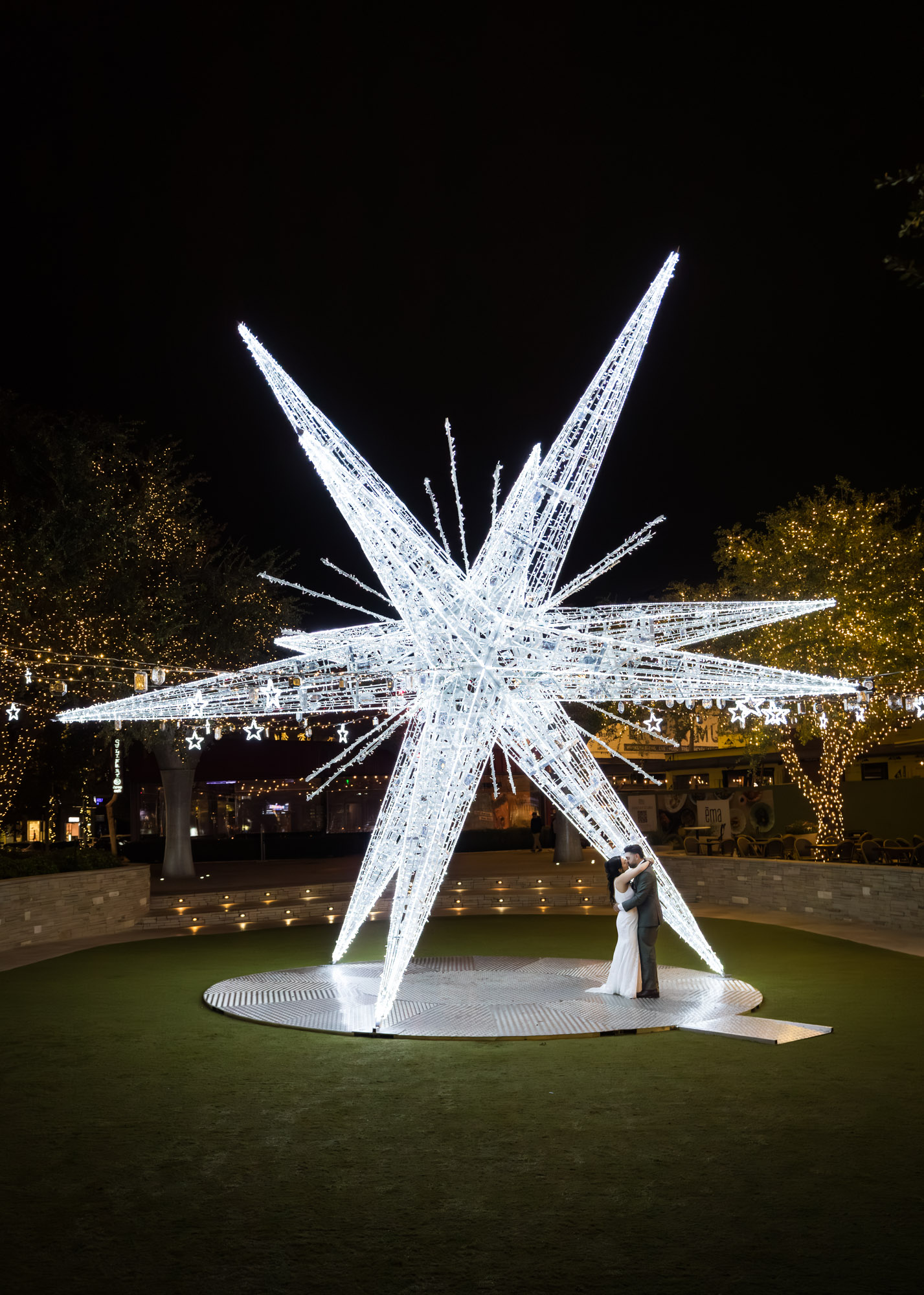 Bride and groom dancing under large white star lit up outside in patio of the Domain in Austin