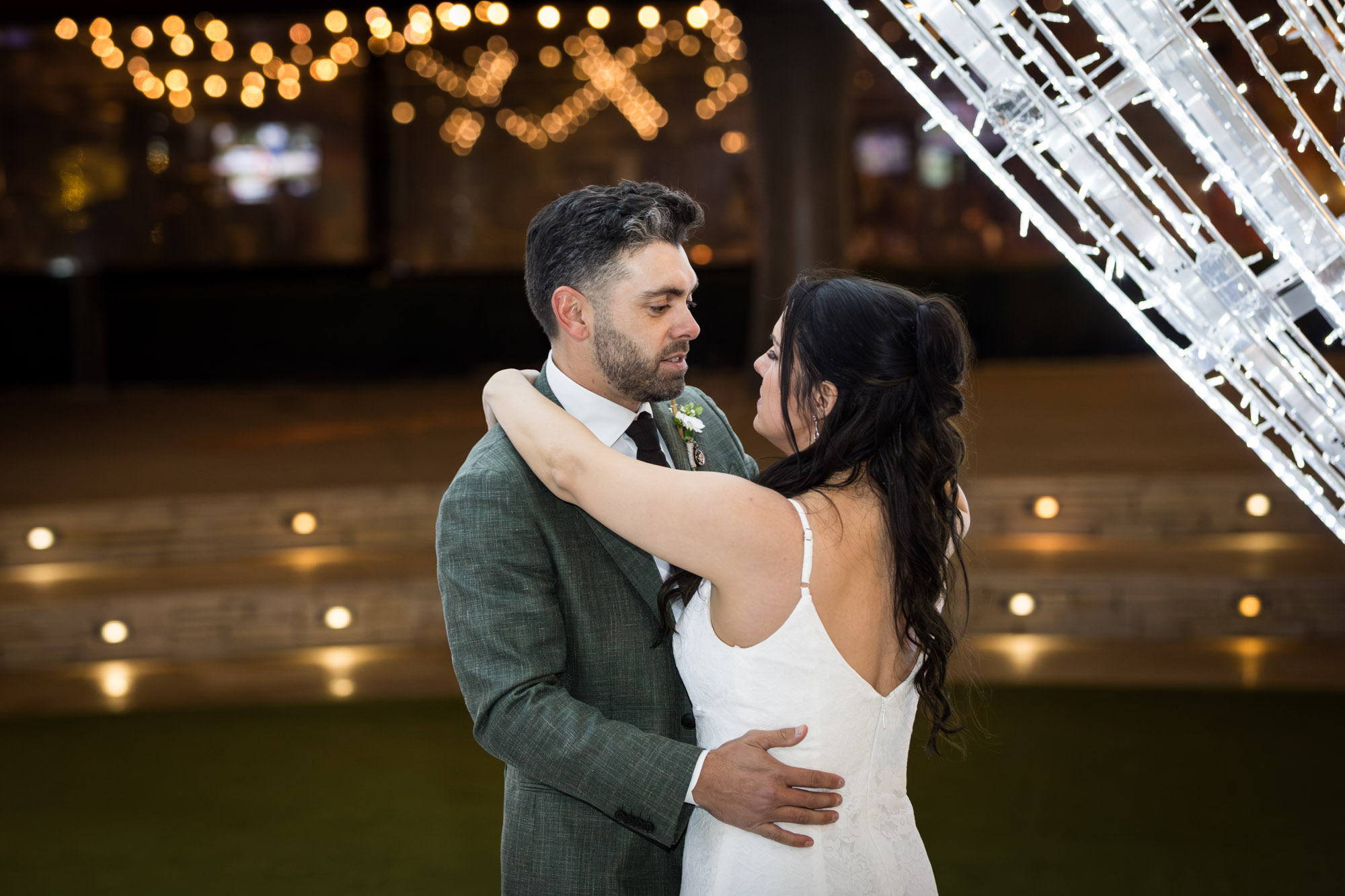 Bride and groom dancing under large white star lit up outside in patio of the Domain in Austin