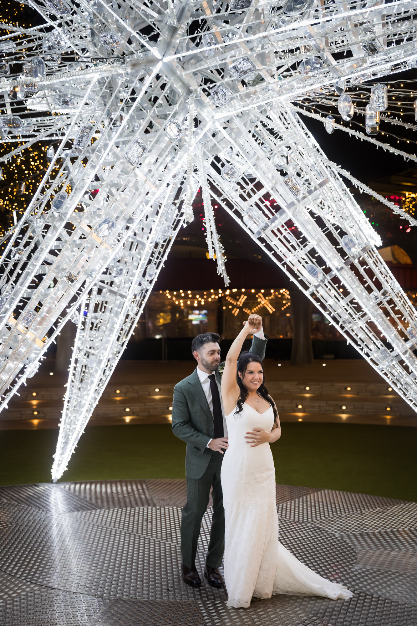 Bride and groom dancing under large white star lit up outside in patio of the Domain in Austin