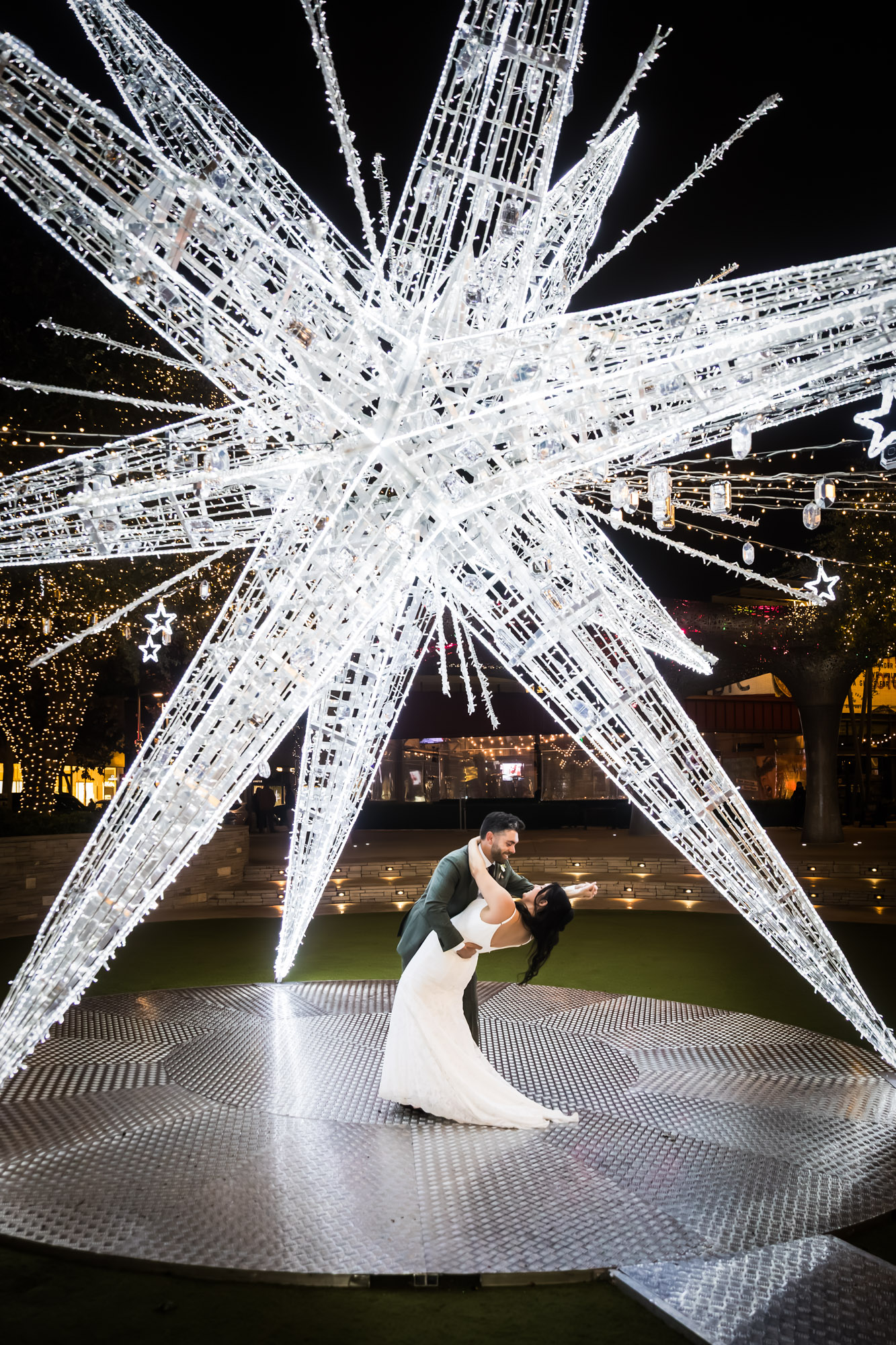 Bride and groom dancing under large white star lit up outside in patio of the Domain in Austin