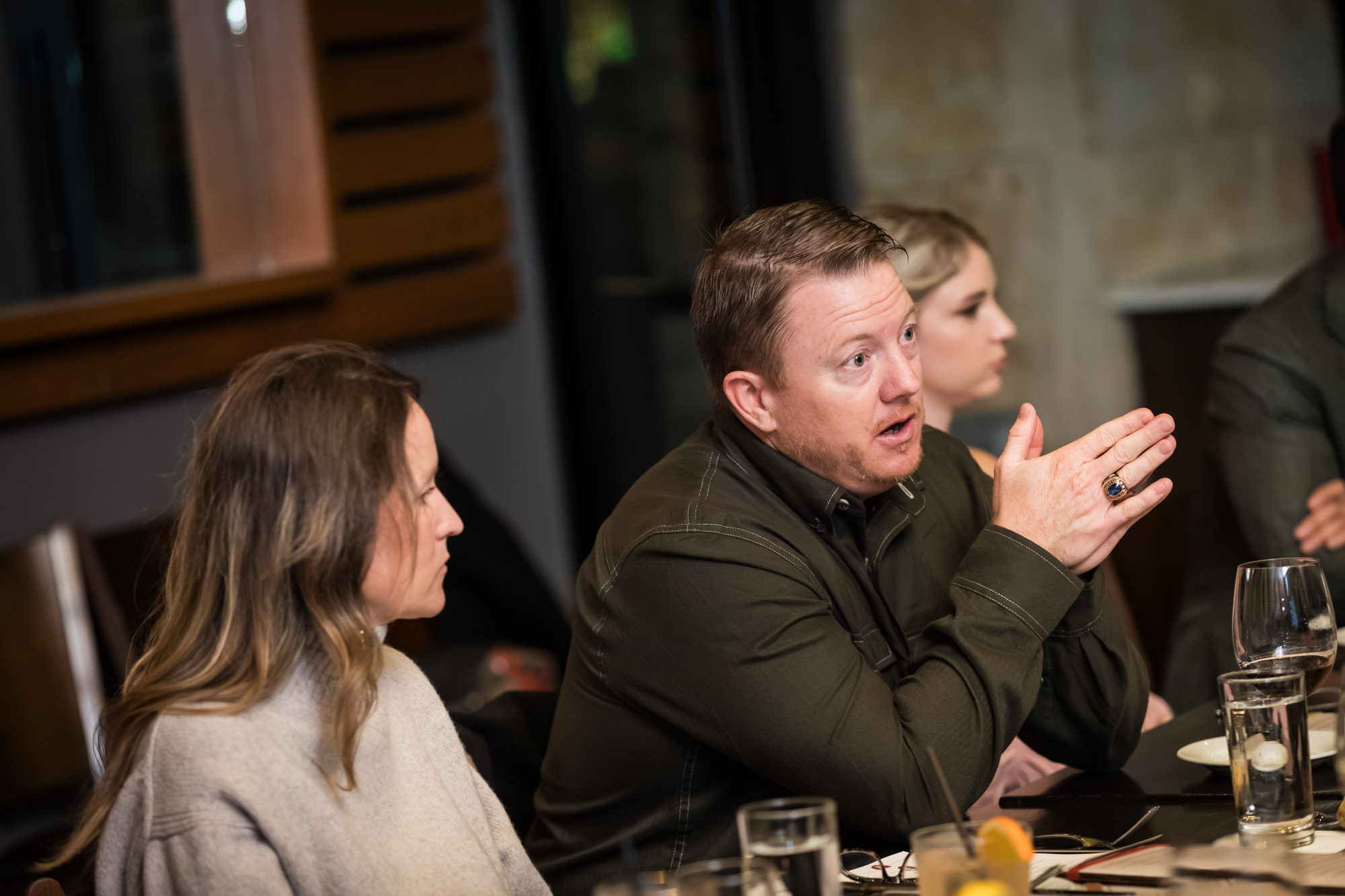 Man seated at table between two women during wedding reception