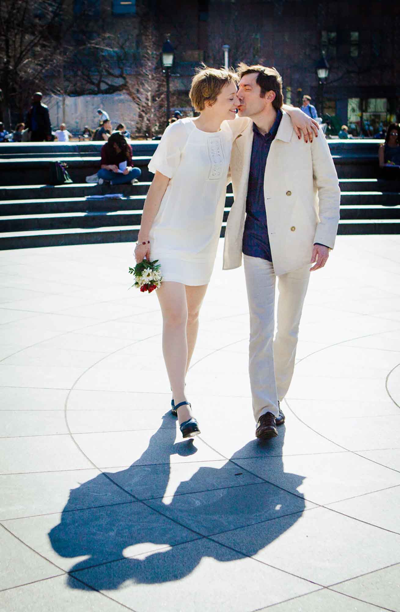 Bride and groom walking together while husband kisses woman on the cheek on concrete walkway for article on how to elope in San Antonio