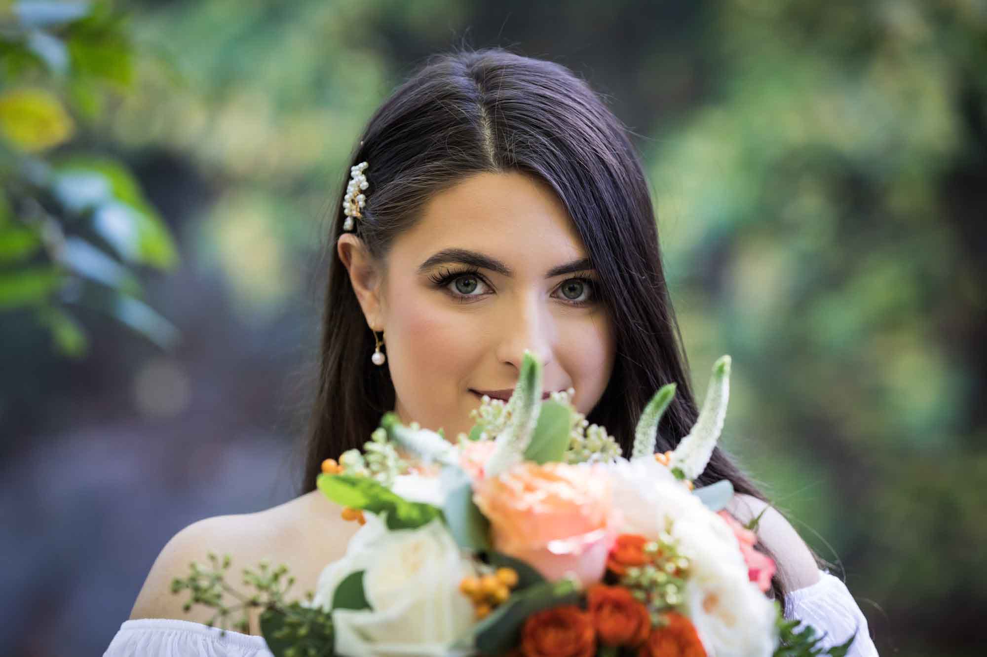 Bride with brown hair looking into camera across from flower bouquet for article on how to elope in San Antonio