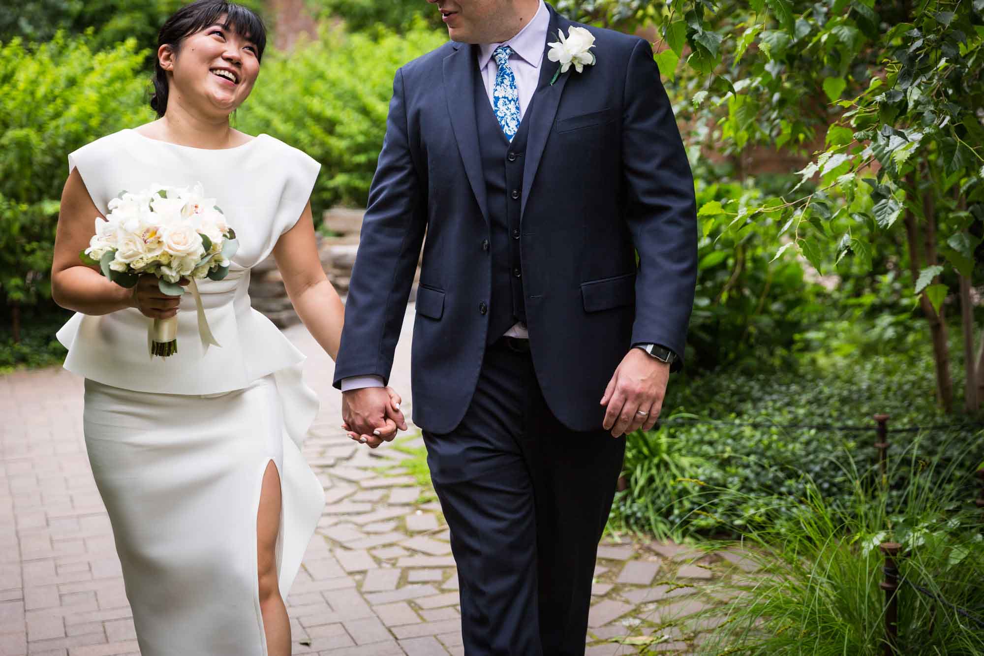 Close up on bride holding flower bouquet holding hands with groom wearing blue, three-piece suit for article on how to elope in San Antonio