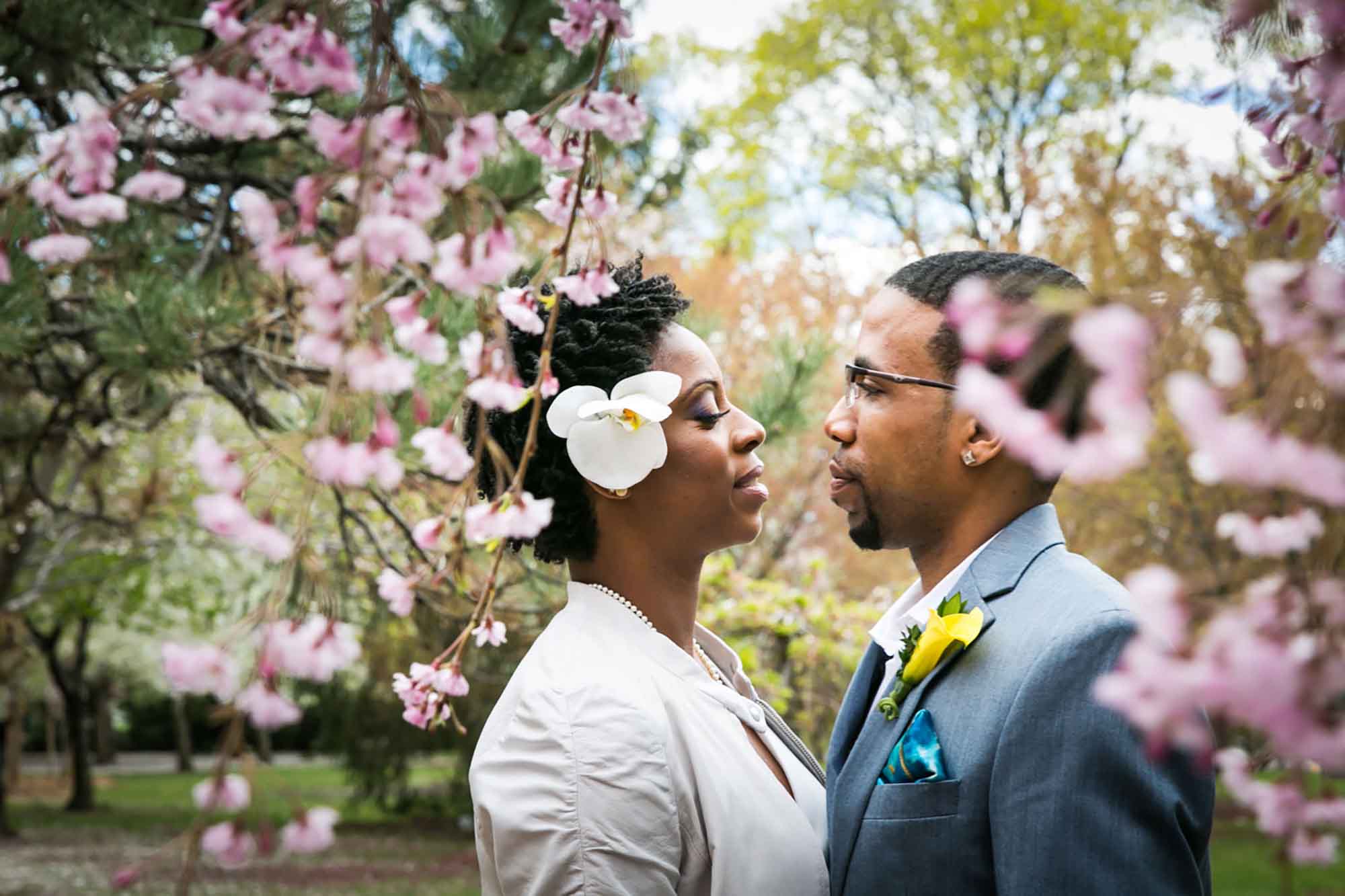 African American bride and groom standing looking at one another in between cherry blossom trees for article on how to elope in San Antonio