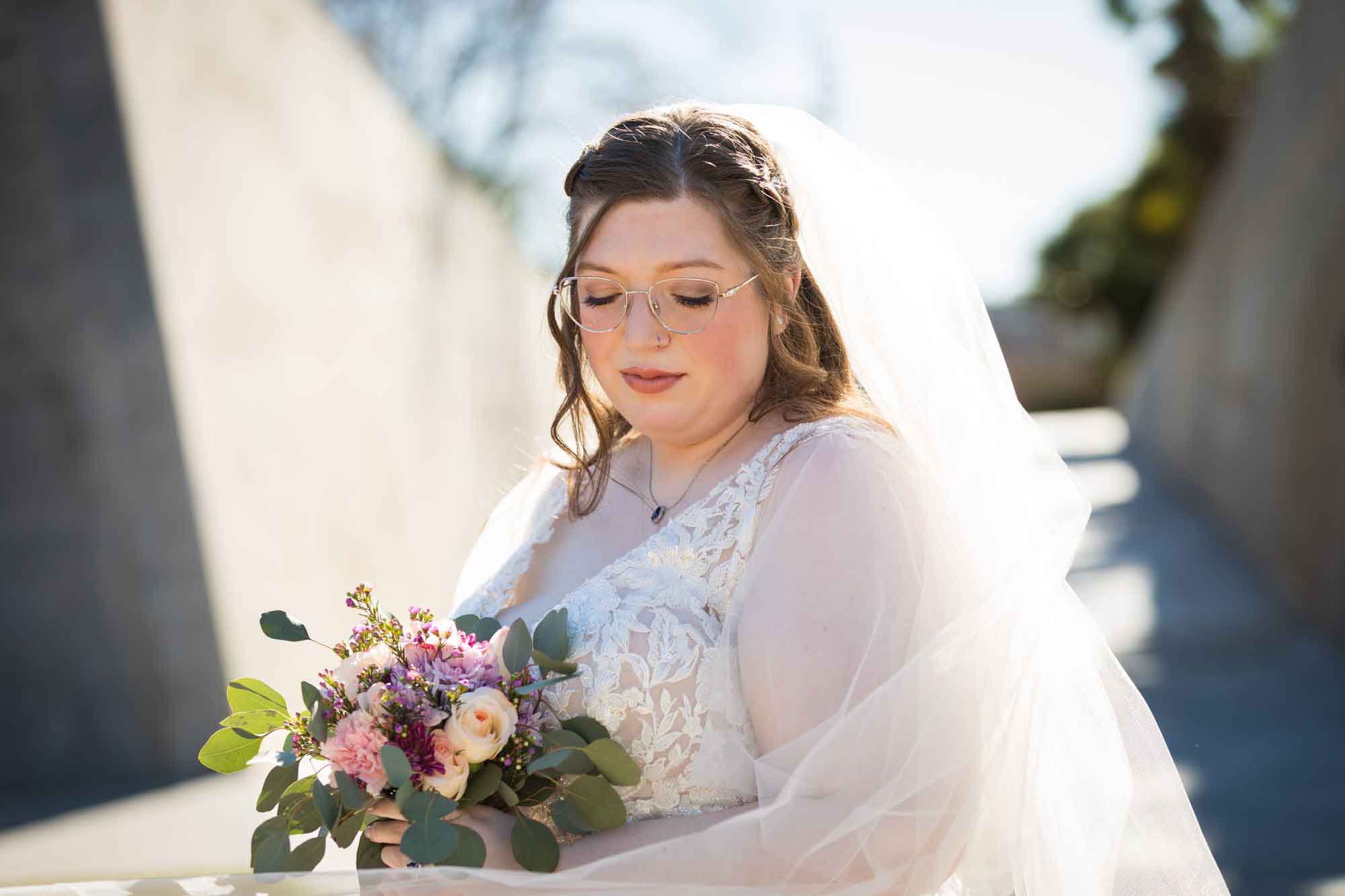 Bride wearing white dress wrapped in veil holding bouquet of flowers during a San Antonio Botanical Gardens bridal portrait session