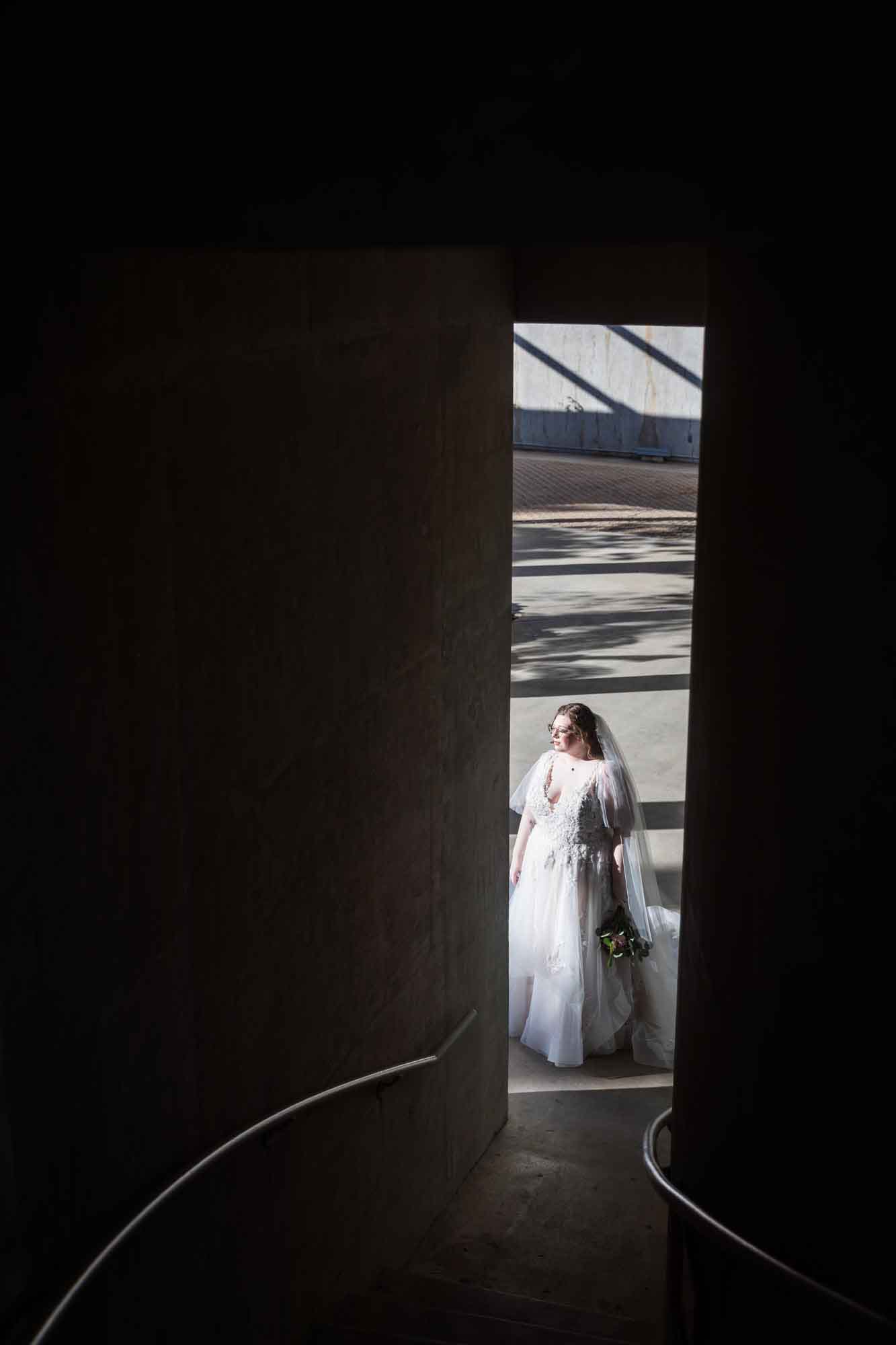 View of bride wearing white dress and veil as seen through stairwell entrance during a San Antonio Botanical Gardens bridal portrait session