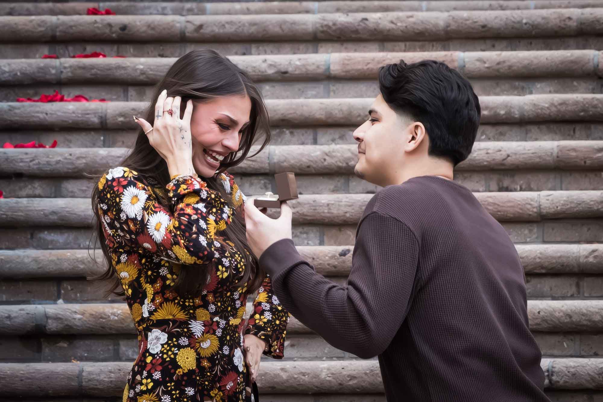 Man proposing to woman in front of the stairs of the Weston Centre during a downtown San Antonio surprise proposal
