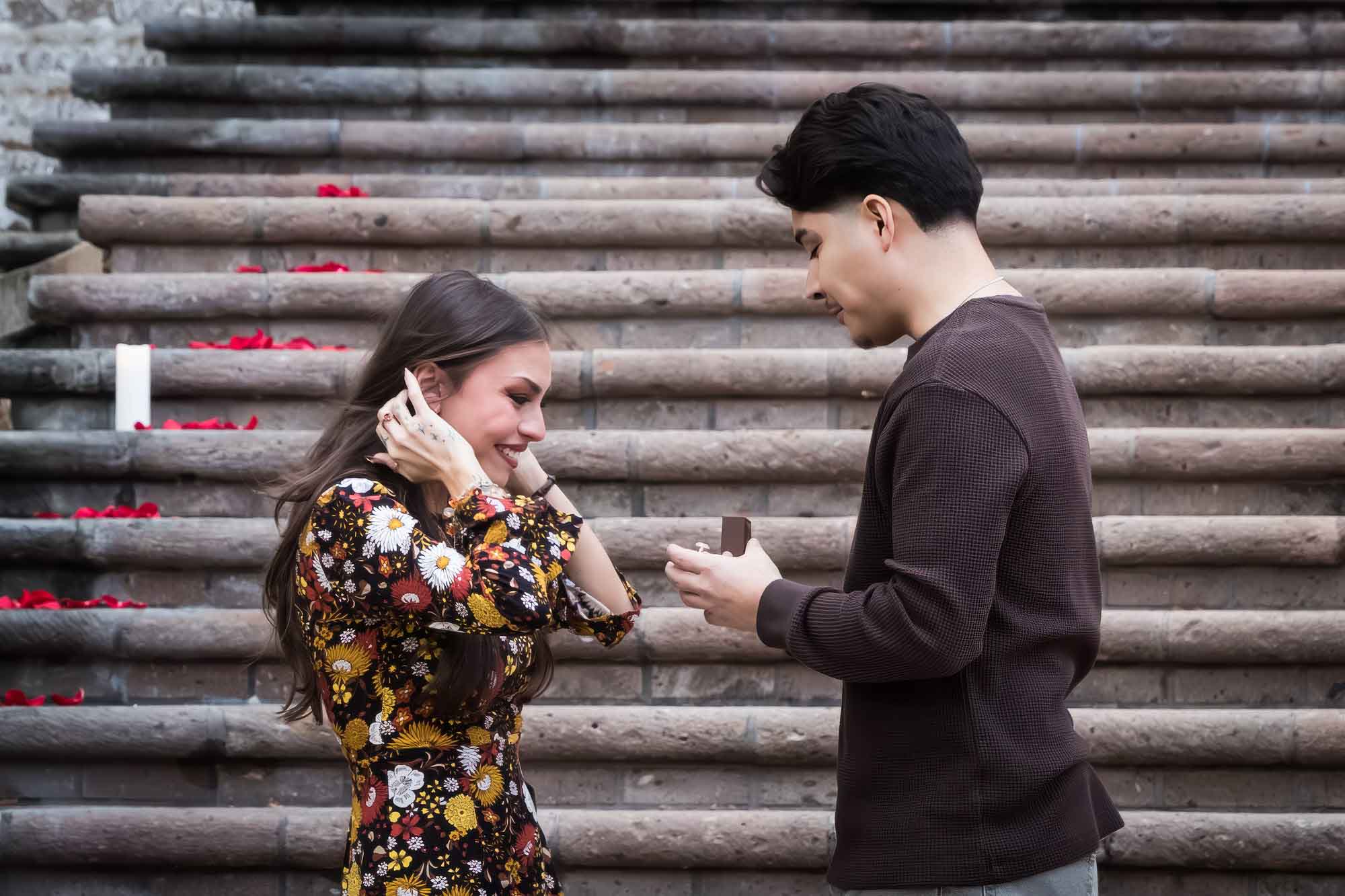 Man proposing to woman in front of the stairs of the Weston Centre during a downtown San Antonio surprise proposal