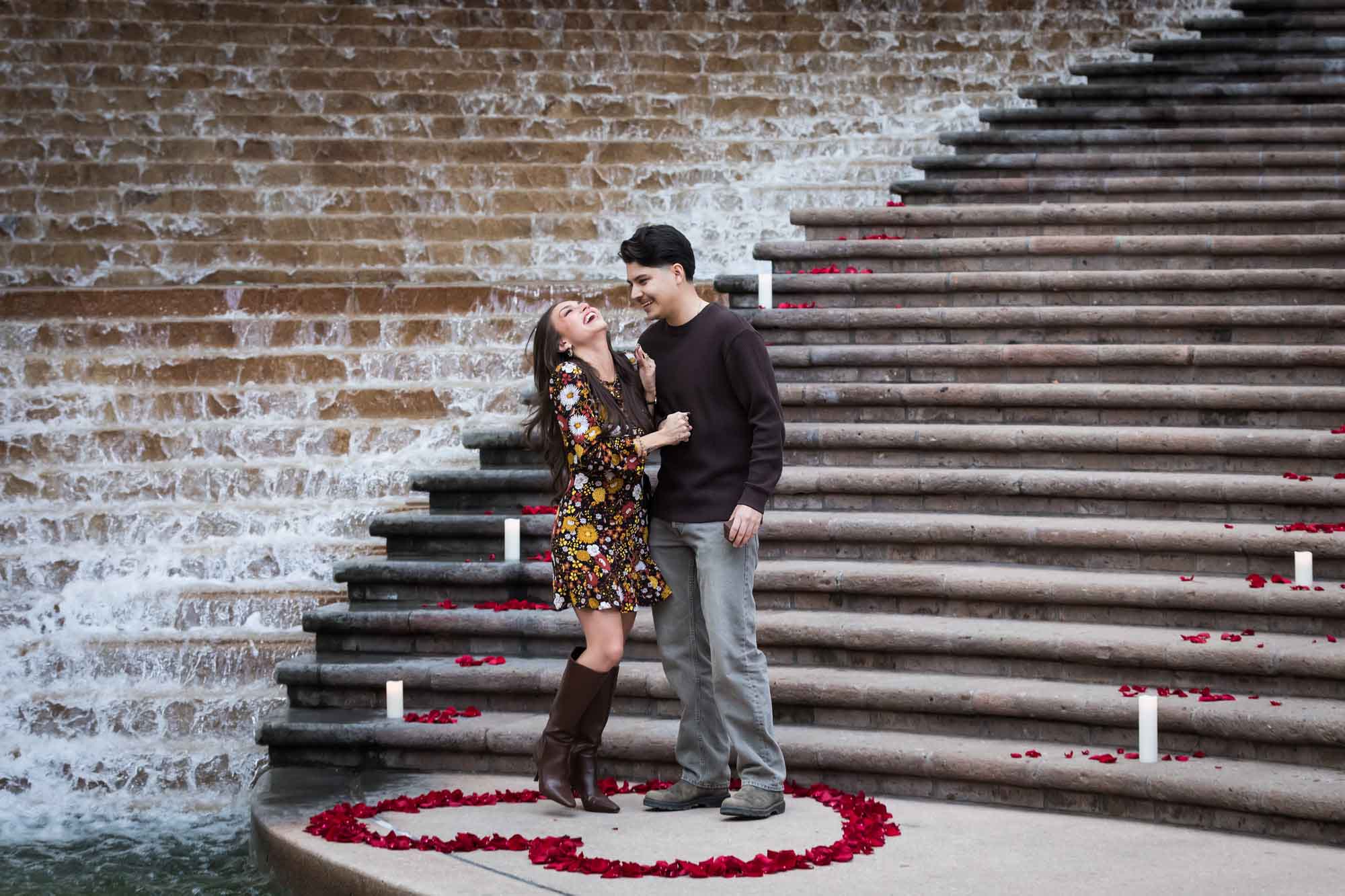 Couple standing in middle of heart-shaped ring of rose petals during a downtown San Antonio surprise proposal