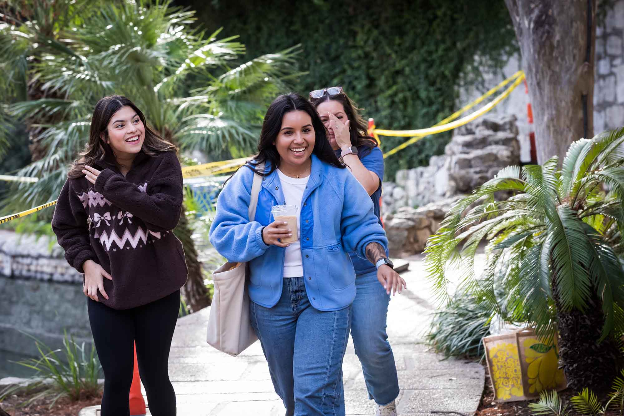 Three women walking rapidly along River Walk during a downtown San Antonio surprise proposal