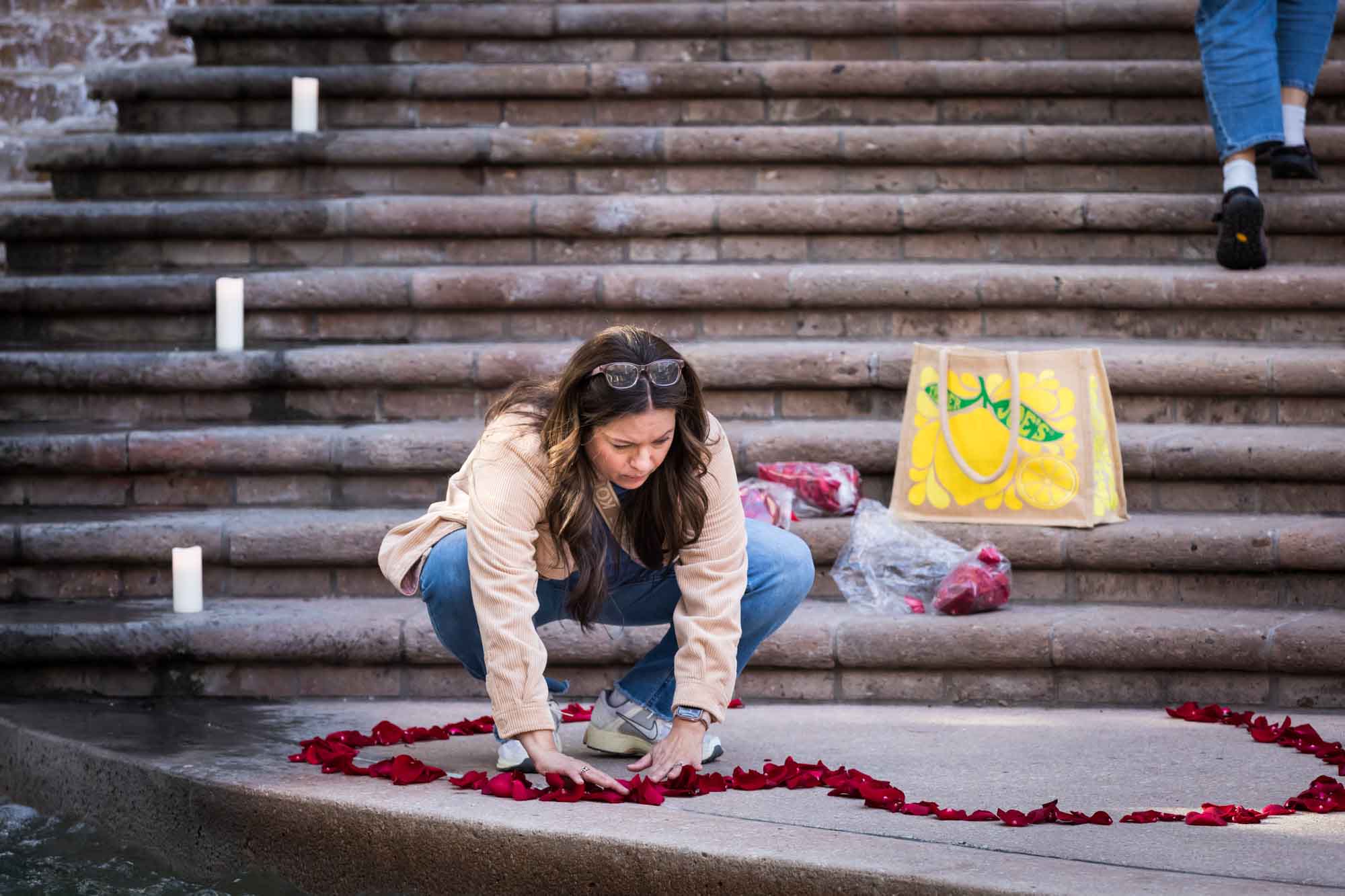 Woman pushing rose petals into the shape of a heart at the base of a staircase in the Weston Centre