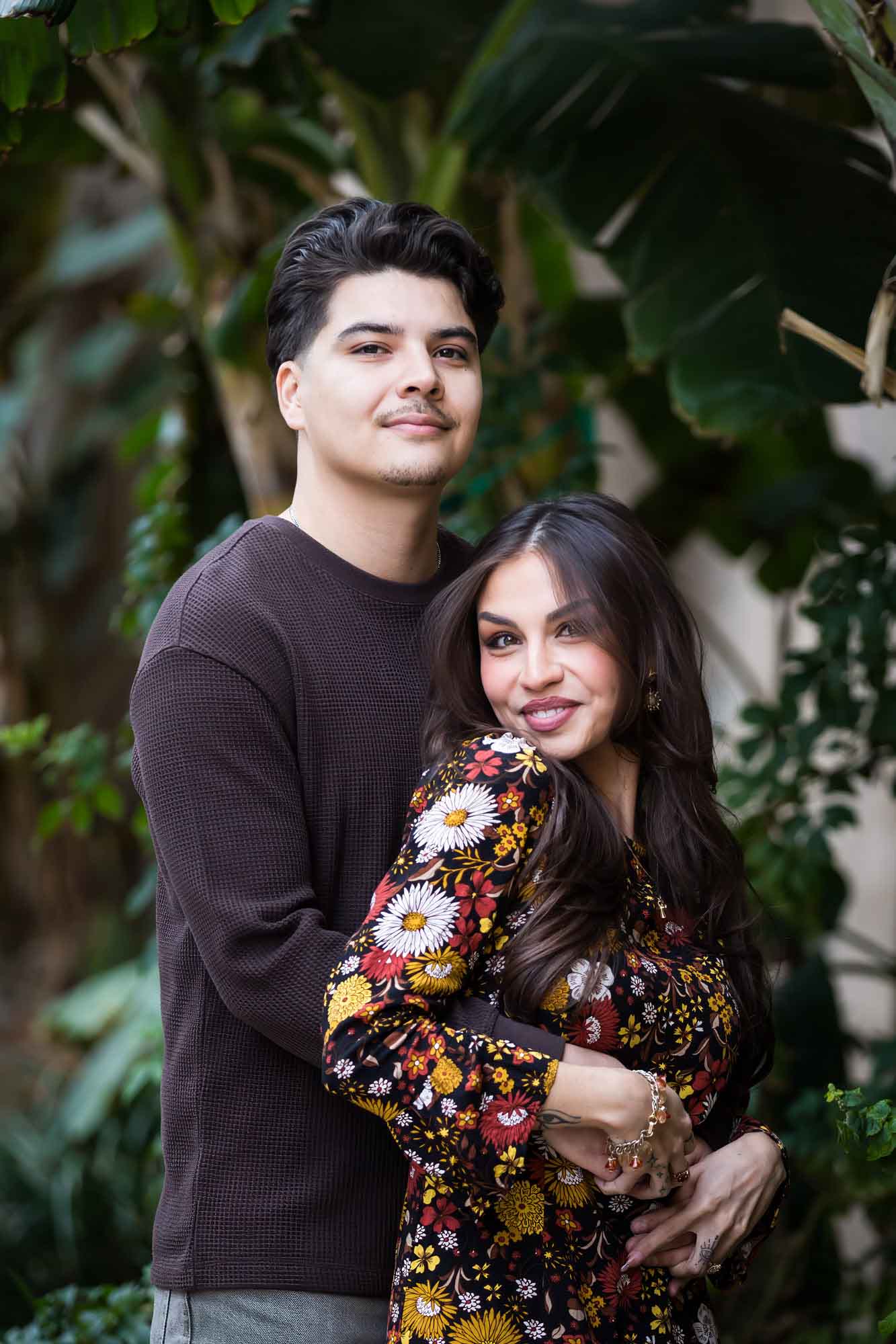 Couple hugging in lush landscaping of River Walk during a downtown San Antonio surprise proposal