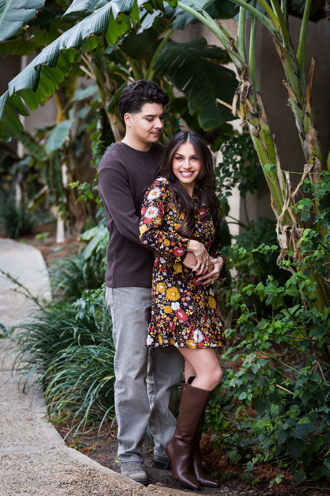 Couple hugging in lush landscaping of River Walk during a downtown San Antonio surprise proposal