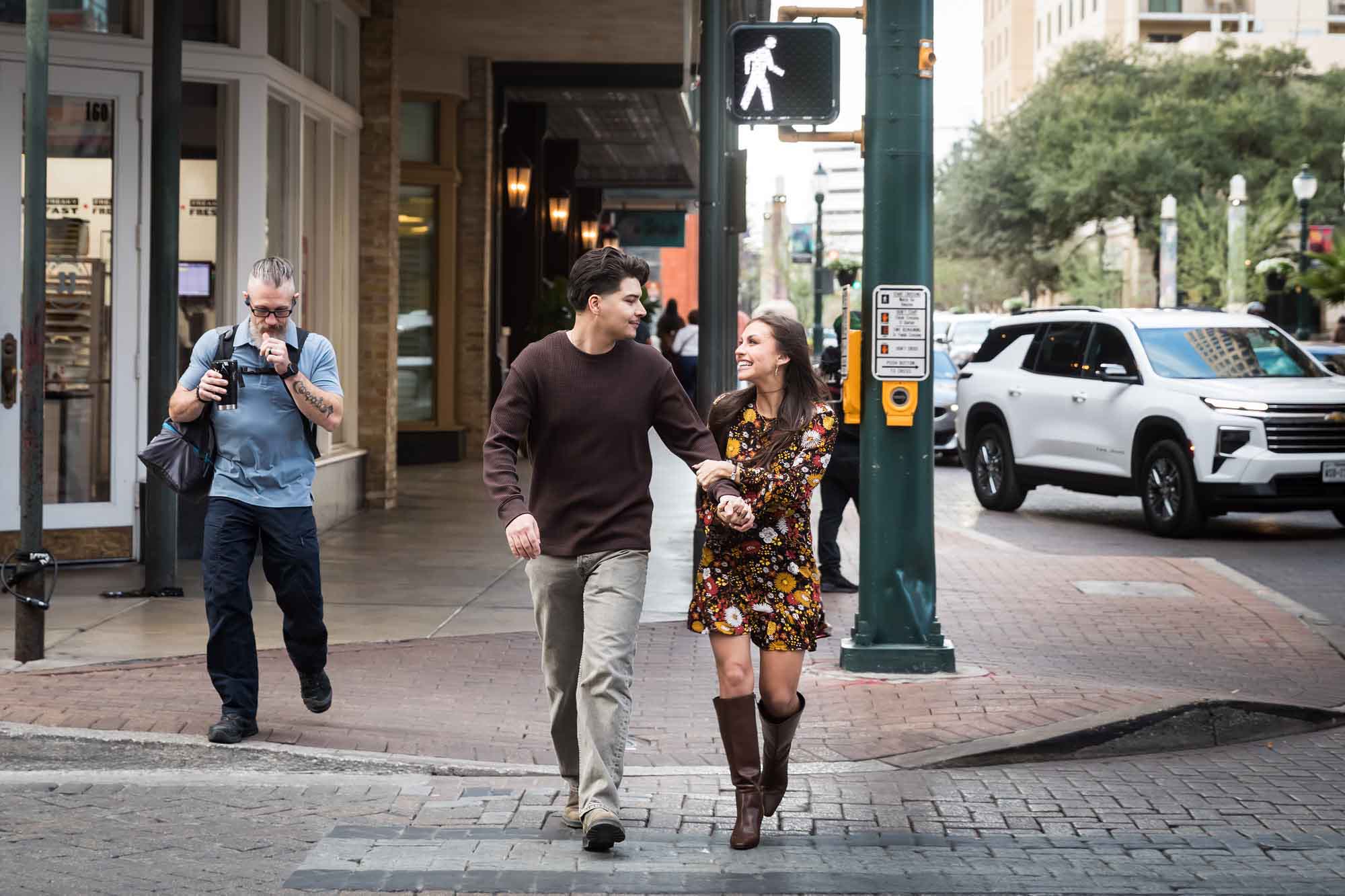 Couple holding hands and crossing busy street during a downtown San Antonio surprise proposal