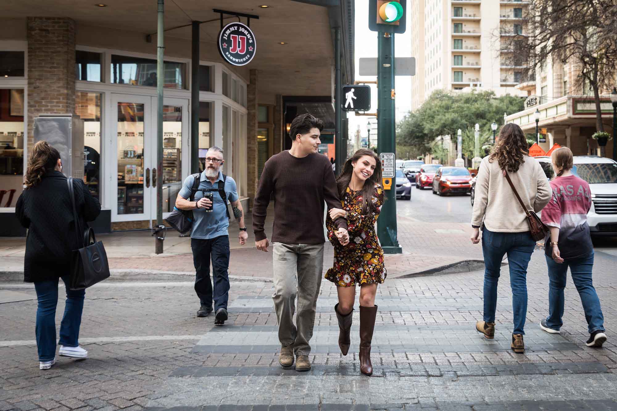 Couple holding hands and crossing busy street during a downtown San Antonio surprise proposal