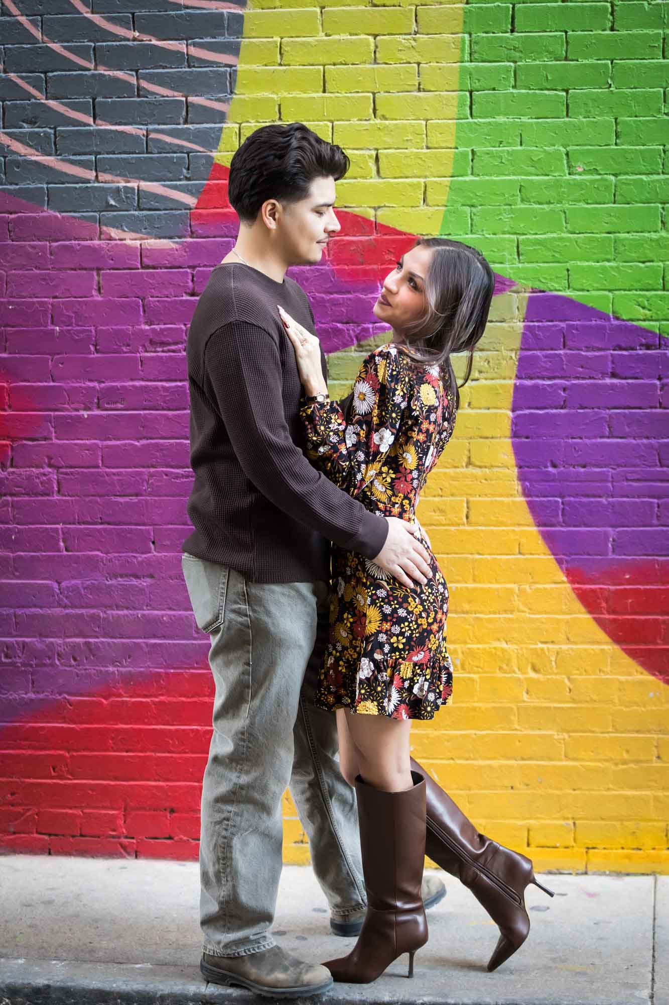 Couple hugging in front of colorful brick wall during a downtown San Antonio surprise proposal