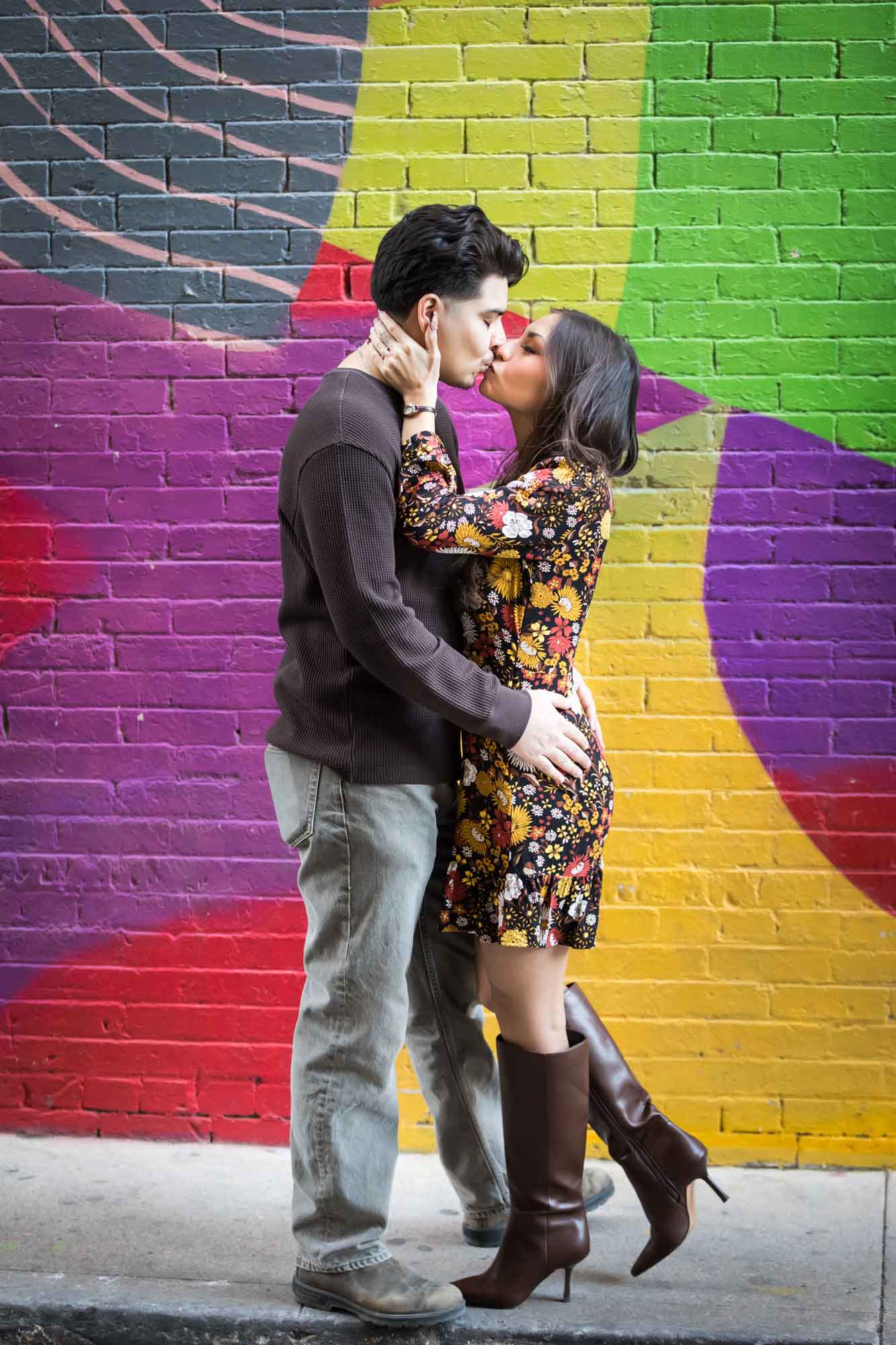 Couple kissing in front of colorful brick wall during a downtown San Antonio surprise proposal